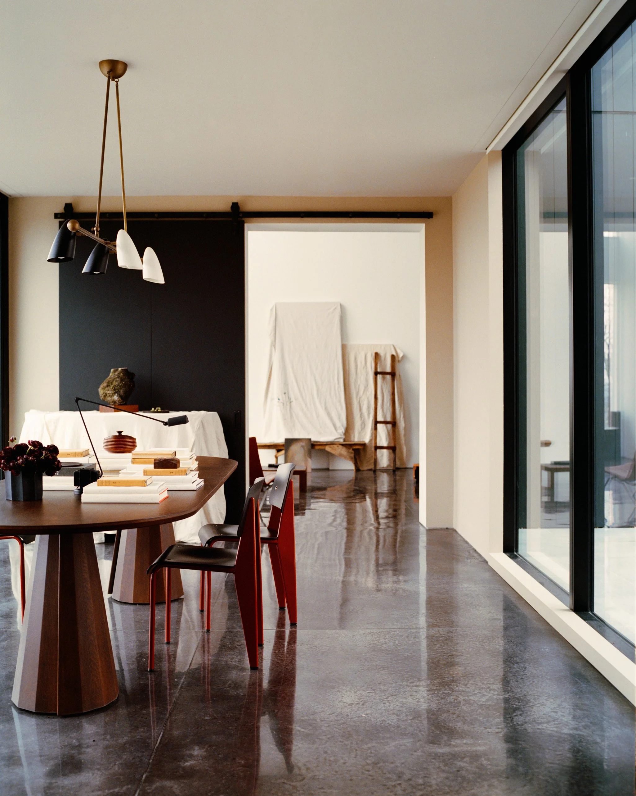 Dining room with a sculptural wood table and polished concrete floors at a Ghent, NY home by JG Neukomm Architecture