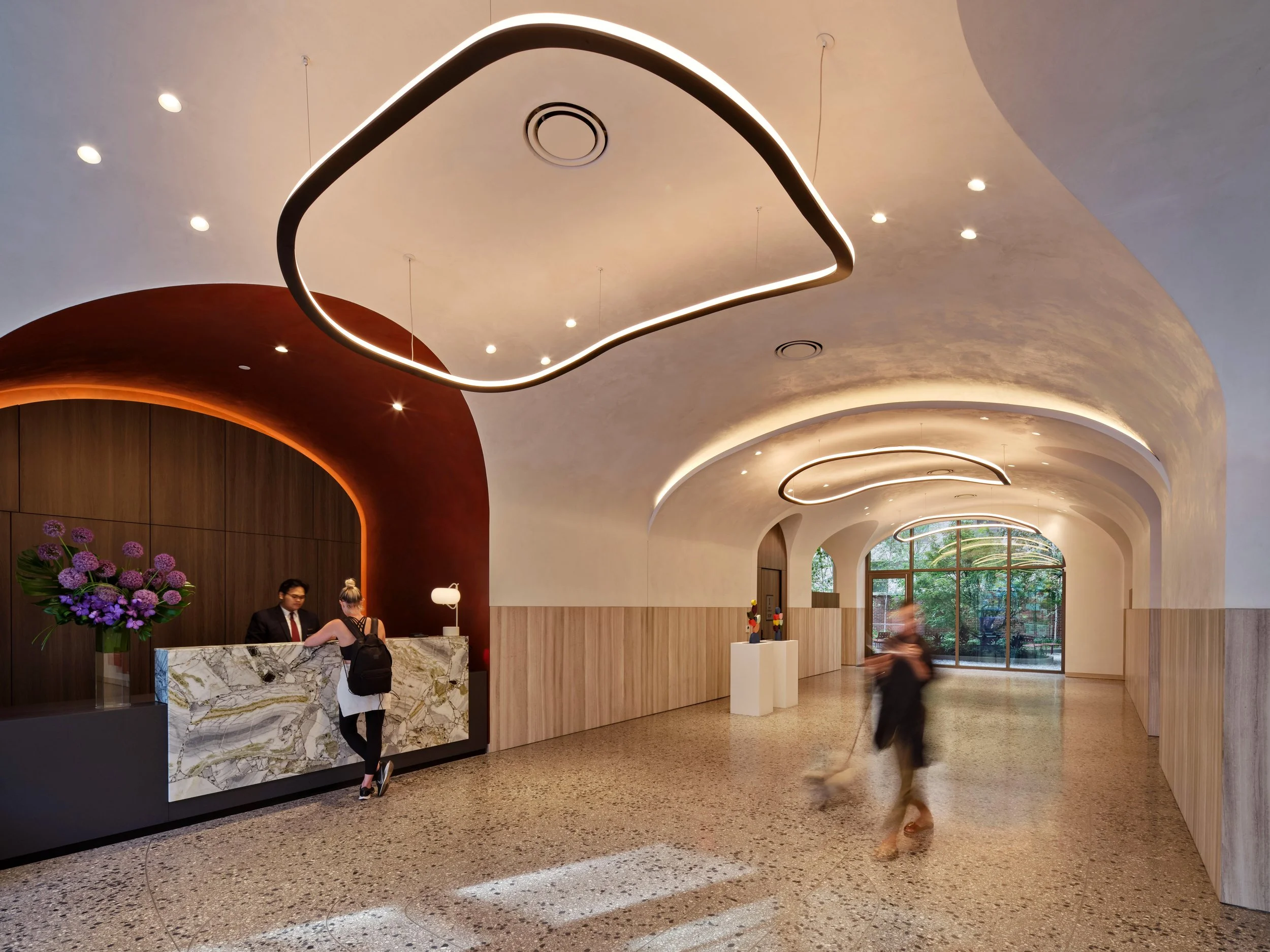 Lobby with a sculptural arched plaster ceiling and illuminated ring pendants at The Suffolk, a Lower East Side residential building, interiors by JG Neukomm Architecture