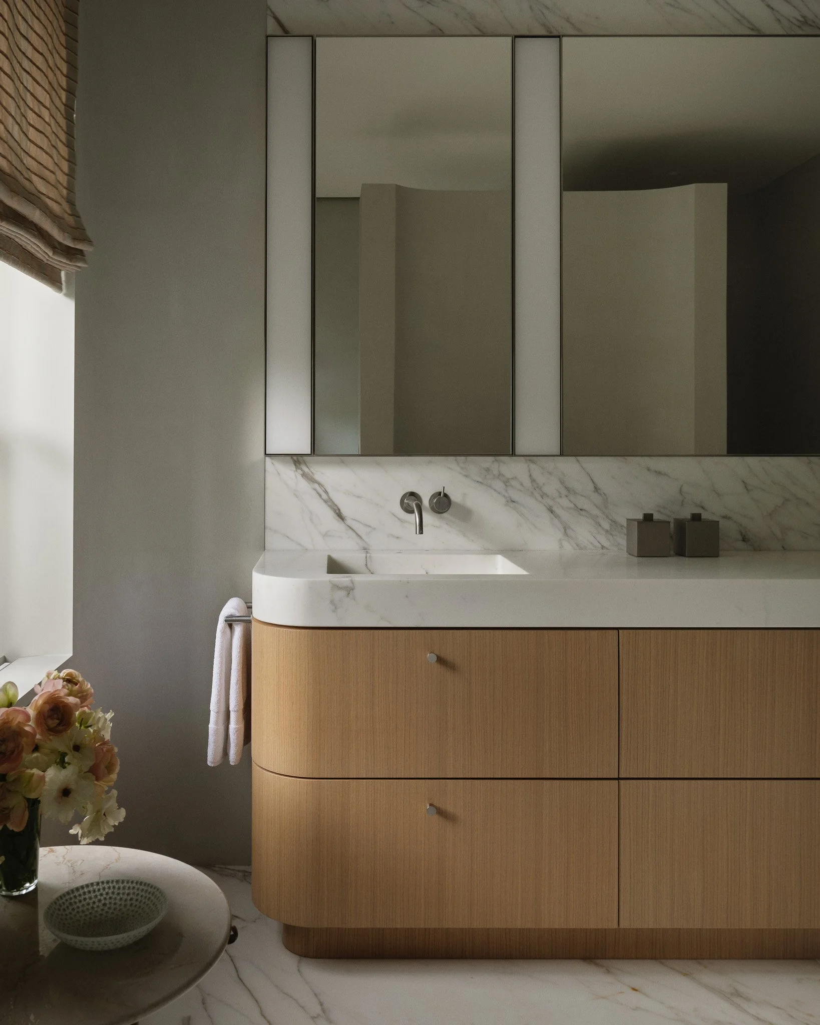 Bathroom with a marble countertop and a custom wood vanity in a West Village townhouse by JG Neukomm Architecture