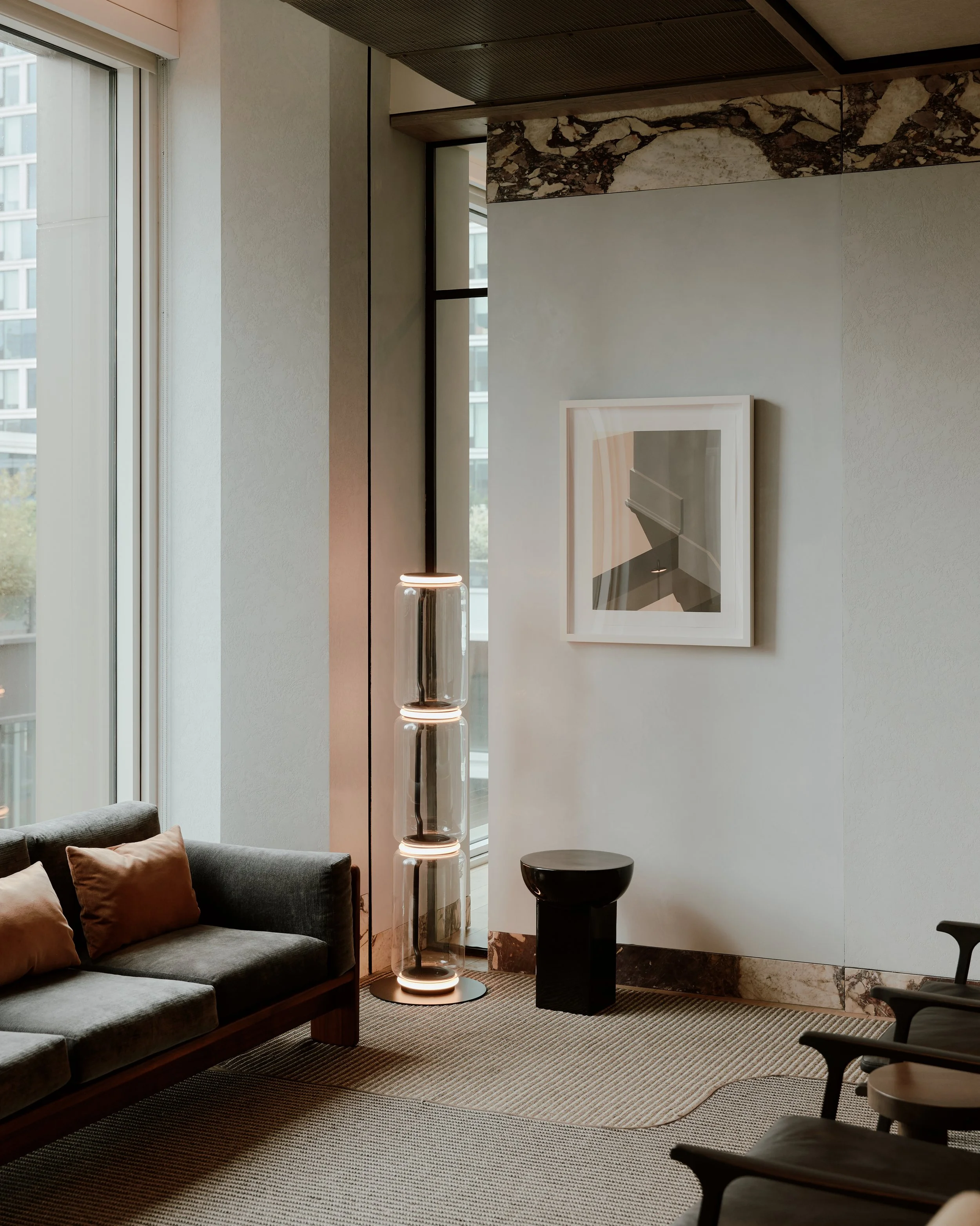 Lounge corner with a sofa, floor lamp, and framed artwork at The Suffolk, a Lower East Side residential building, interiors by JG Neukomm Architecture