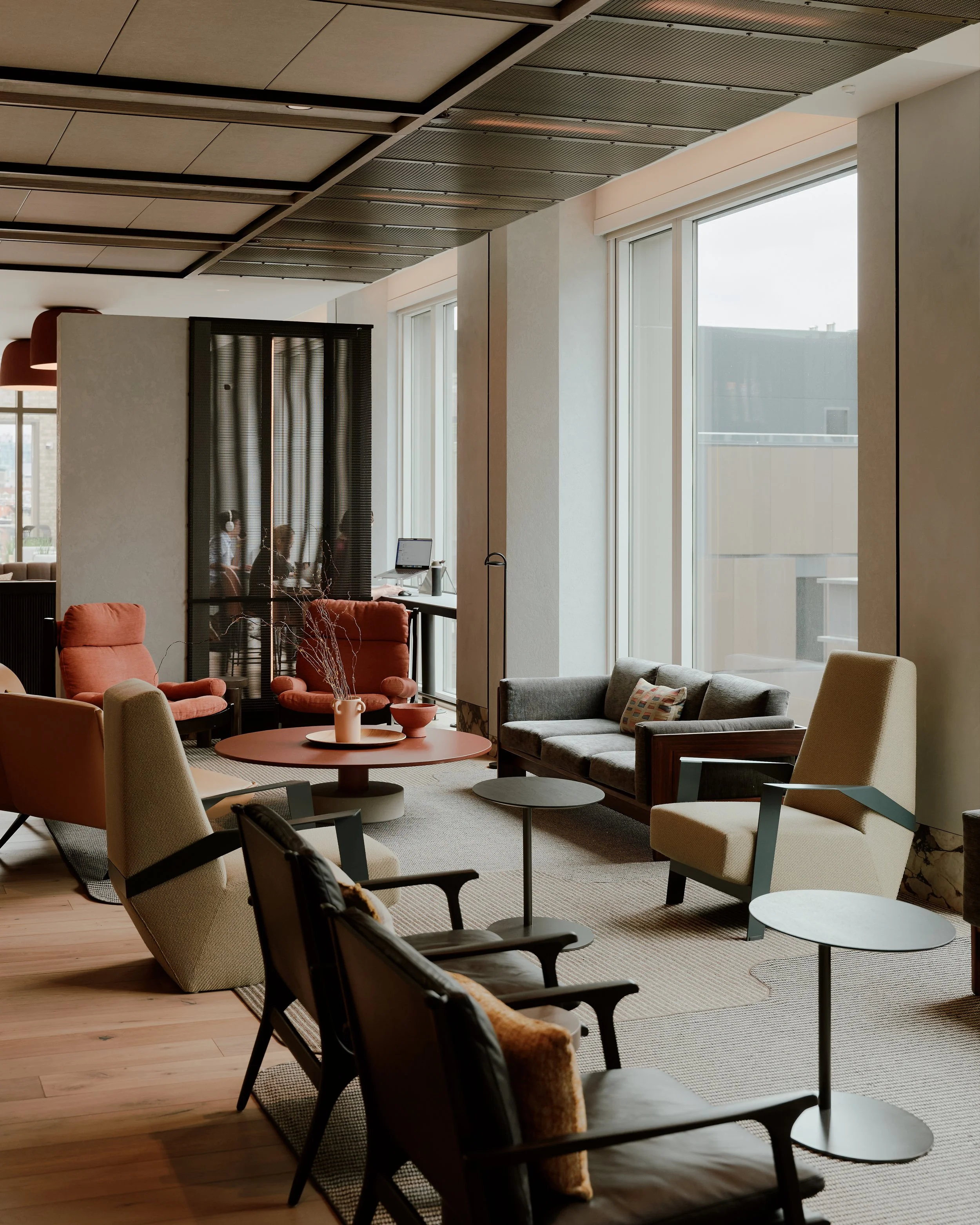 Amenity lounge with mid-century and rust lounge chairs at The Suffolk, a Lower East Side residential building, interiors by JG Neukomm Architecture