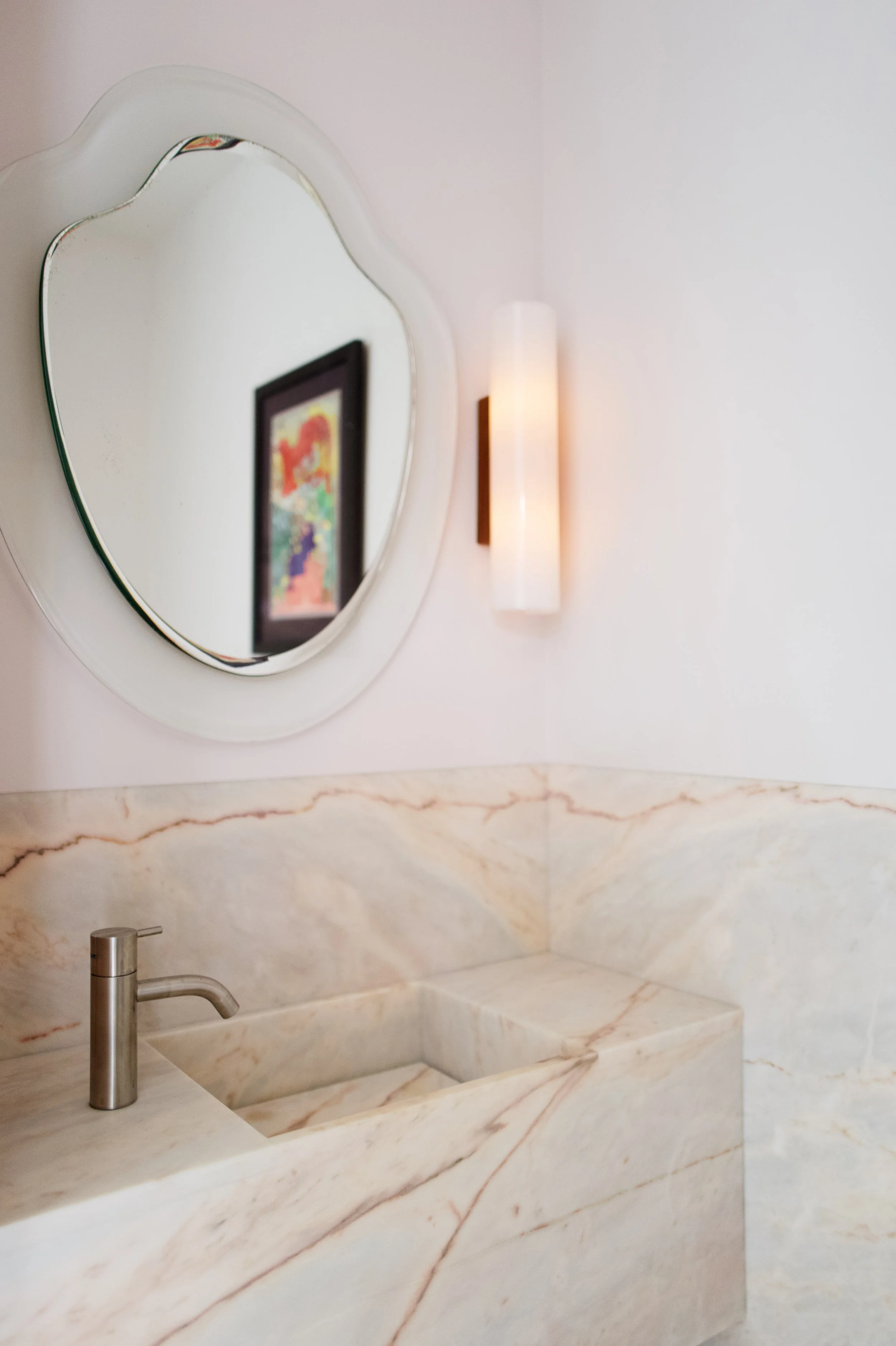 Powder room with veined marble and an integrated stone sink in a West Village townhouse by JG Neukomm Architecture