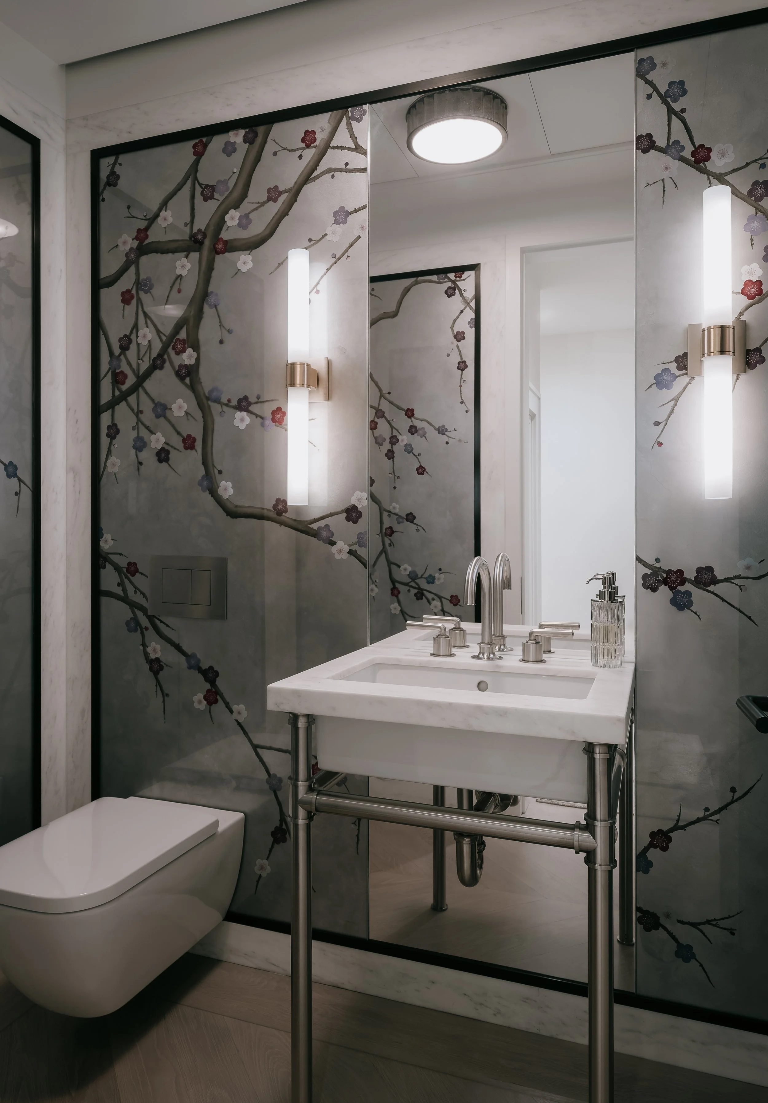 Powder room with cherry-blossom mirrored glass panels and a metal-leg console sink