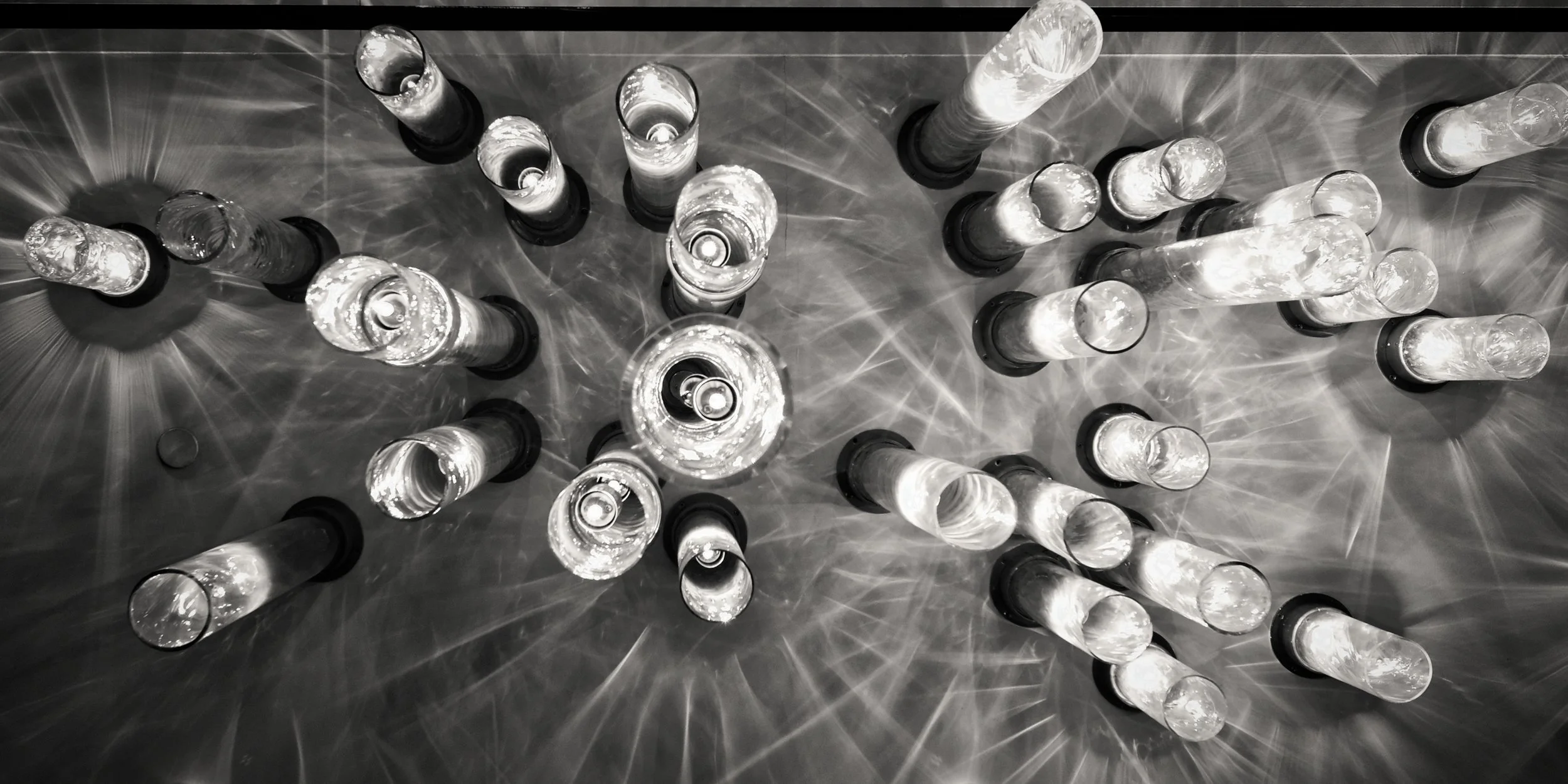 JGNA bar detail of a glass-rod light installation viewed from below in black and white