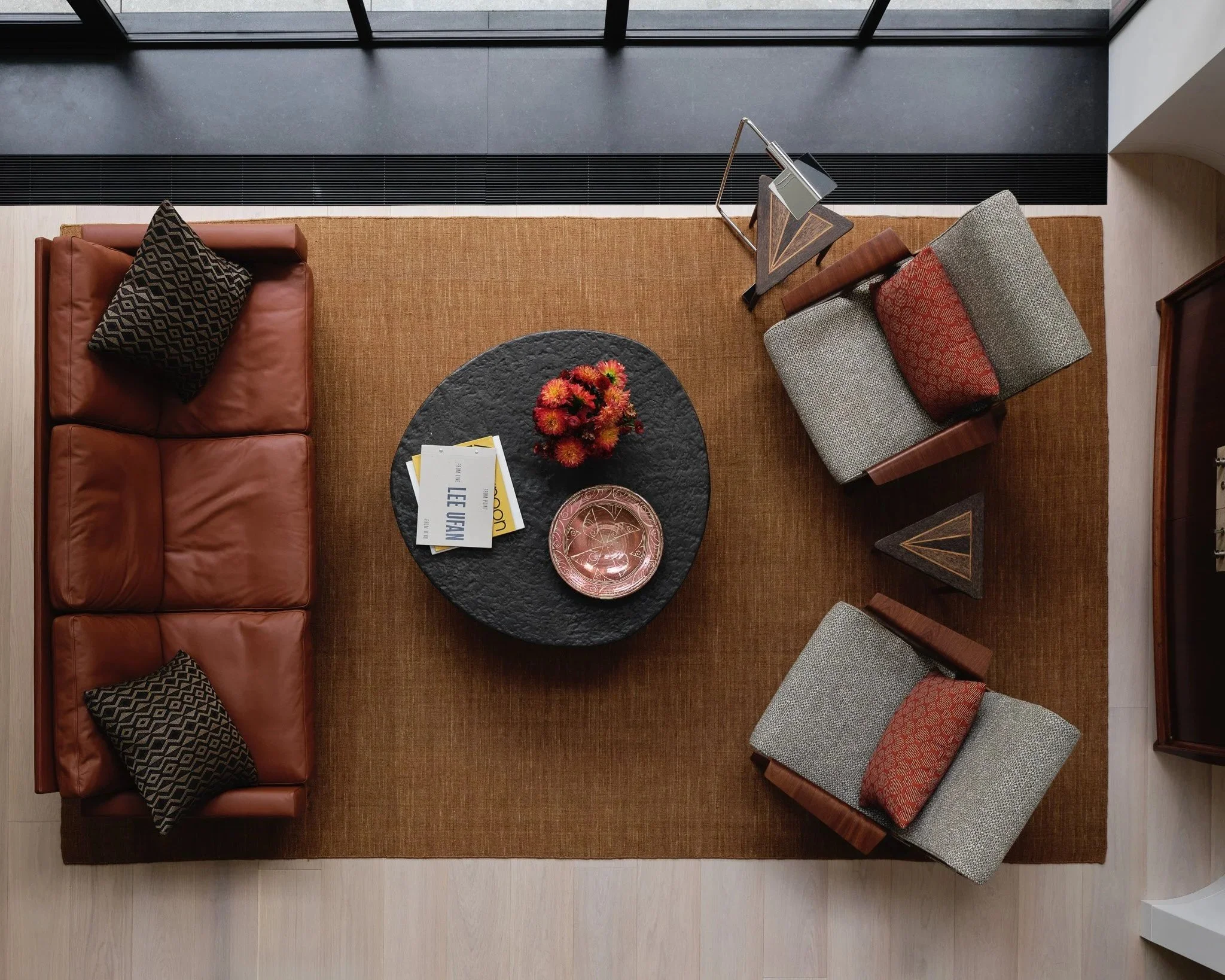 Overhead view of a living room with a leather sofa and upholstered armchairs in a West Village townhouse by JG Neukomm Architecture