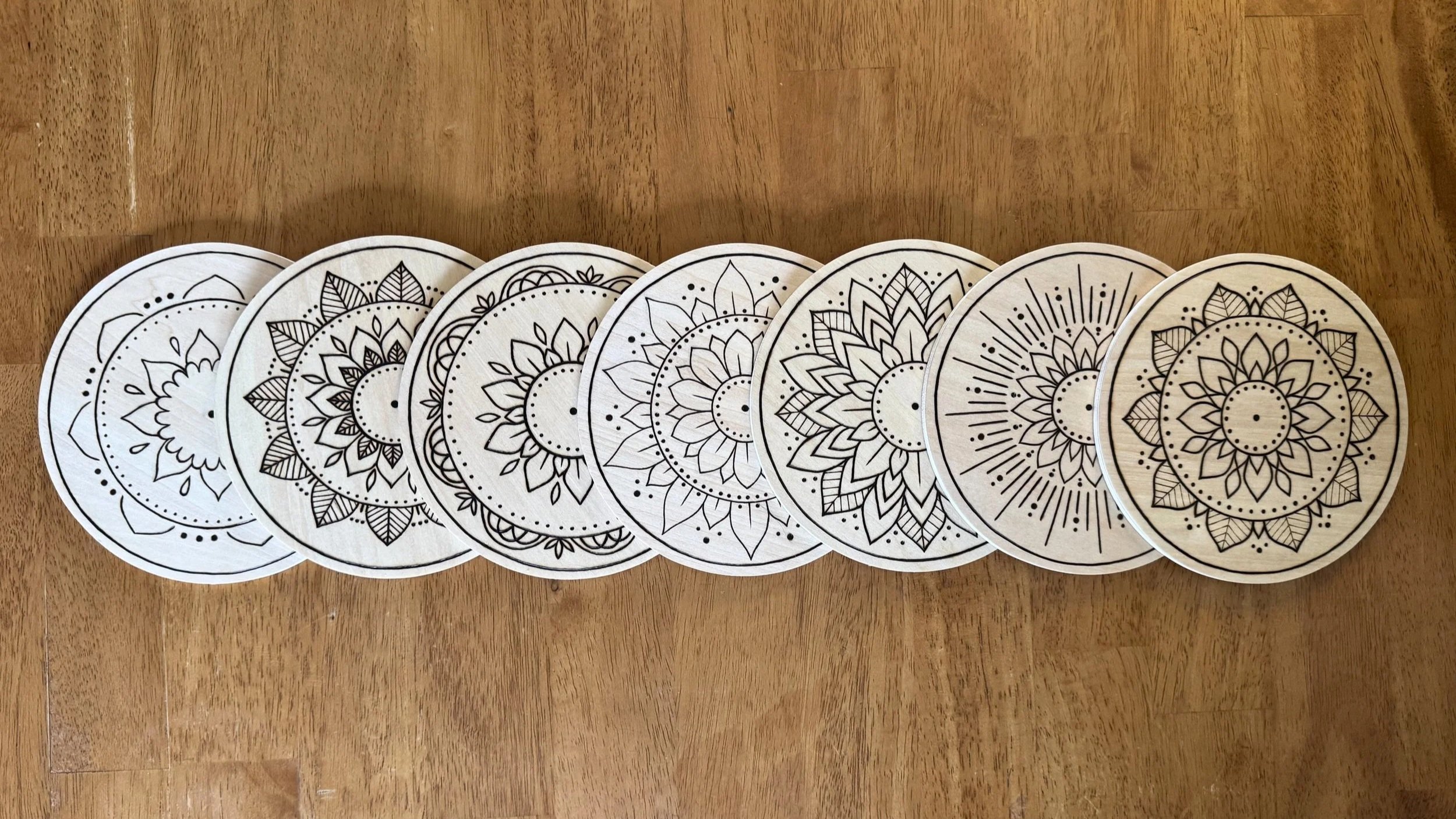 The At the Center mandala collection by Cheyenne Cox, seven hand-burned pyrography mandalas.