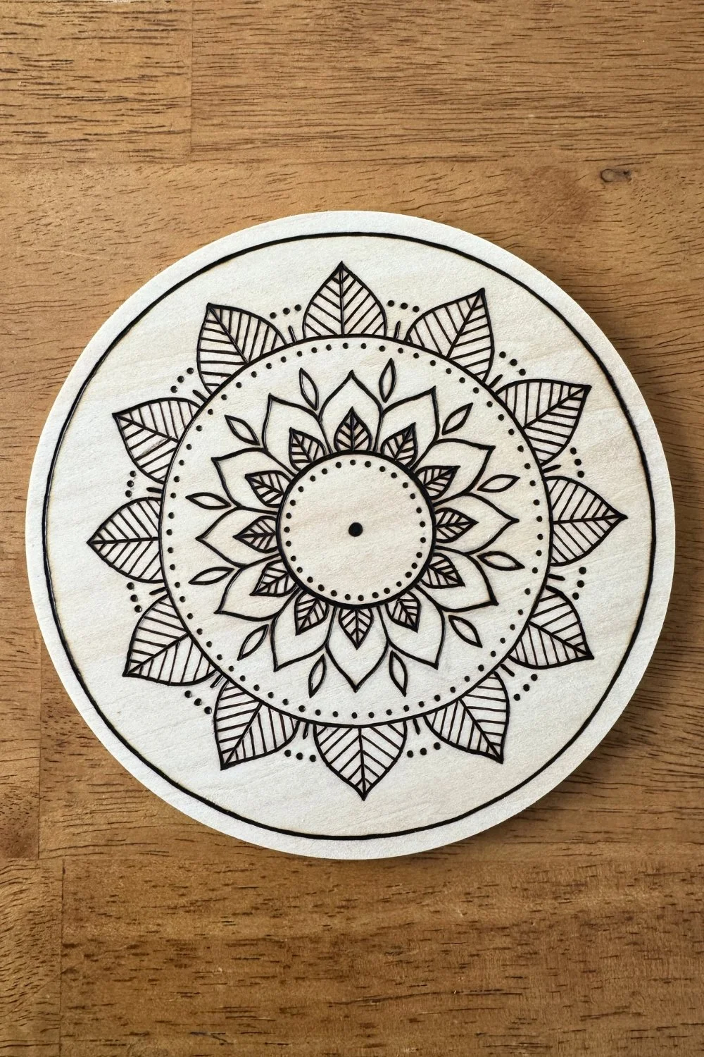 Hand-burned mandala artwork “Rooted” by Cheyenne Wenske, pyrography on birch panel.
