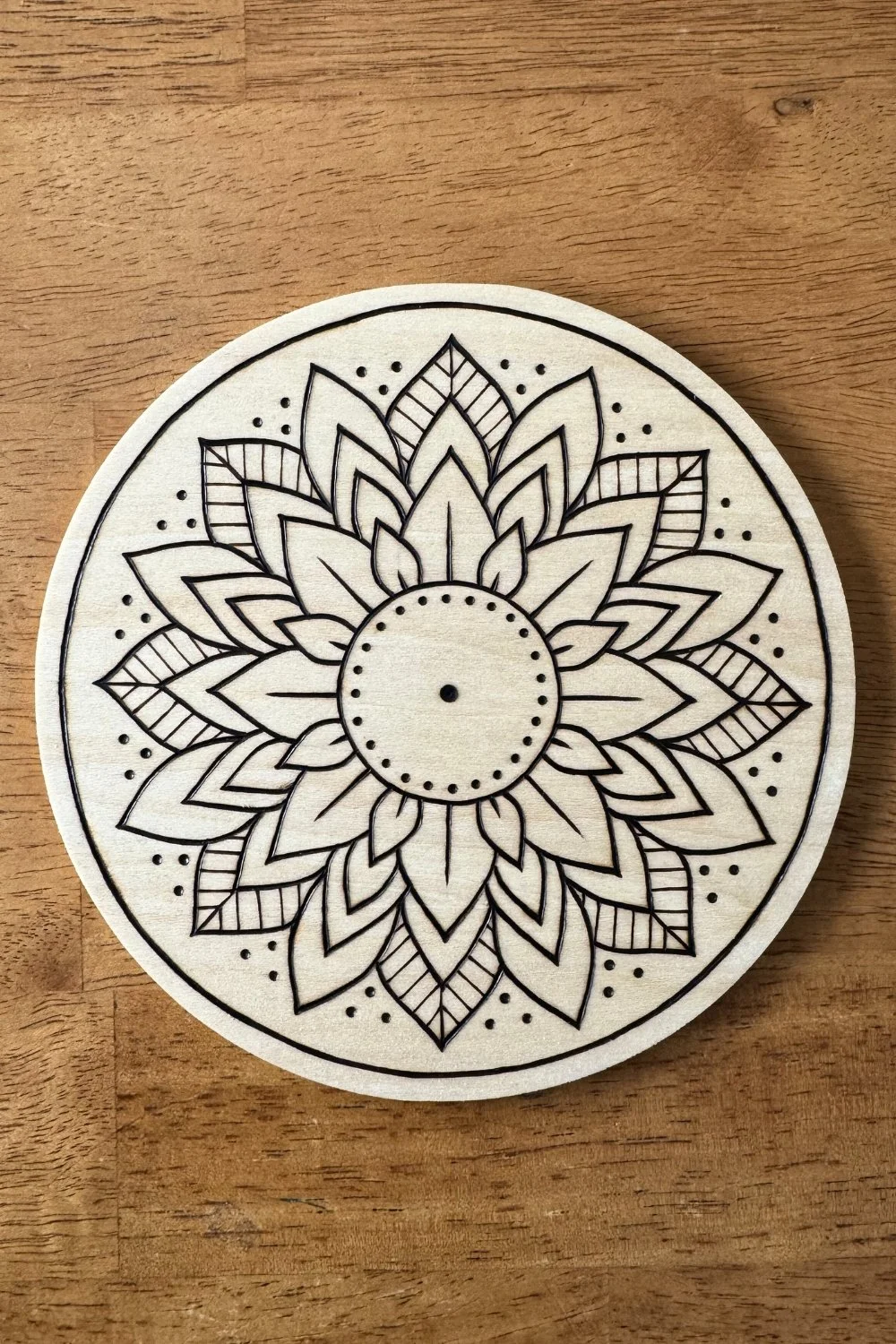 Hand-burned mandala artwork “Bloom” by Cheyenne Wenske, pyrography on birch panel.