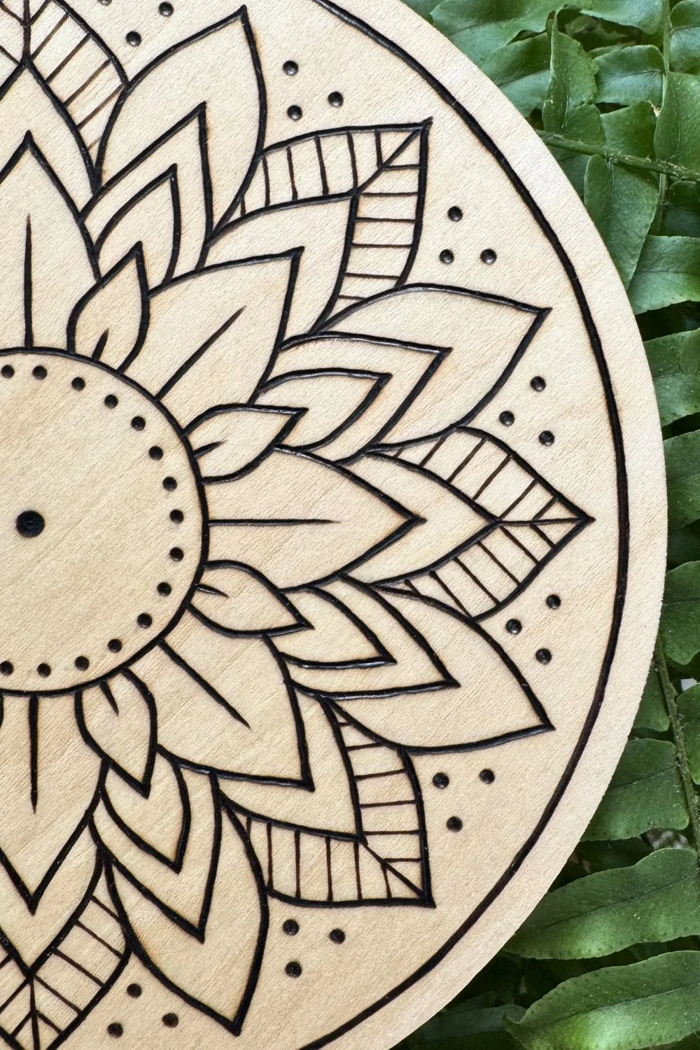 Hand-burned mandala artwork “Bloom” by Cheyenne Wenske, pyrography on birch panel.