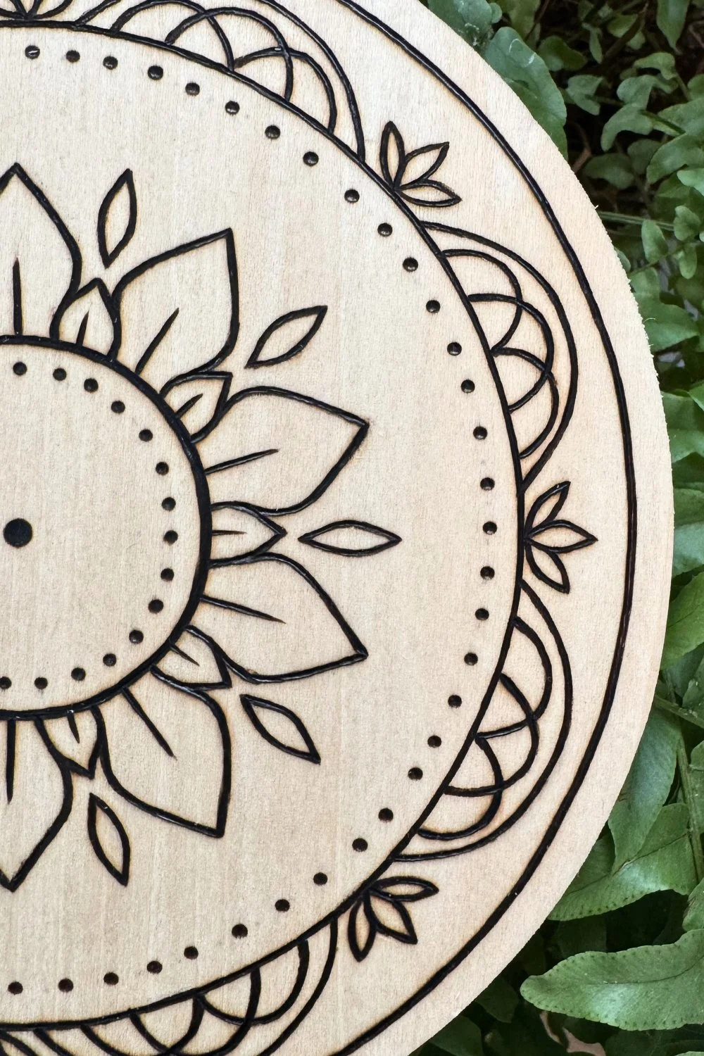 Hand-burned mandala artwork “Held” by Cheyenne Wenske, pyrography on birch panel.