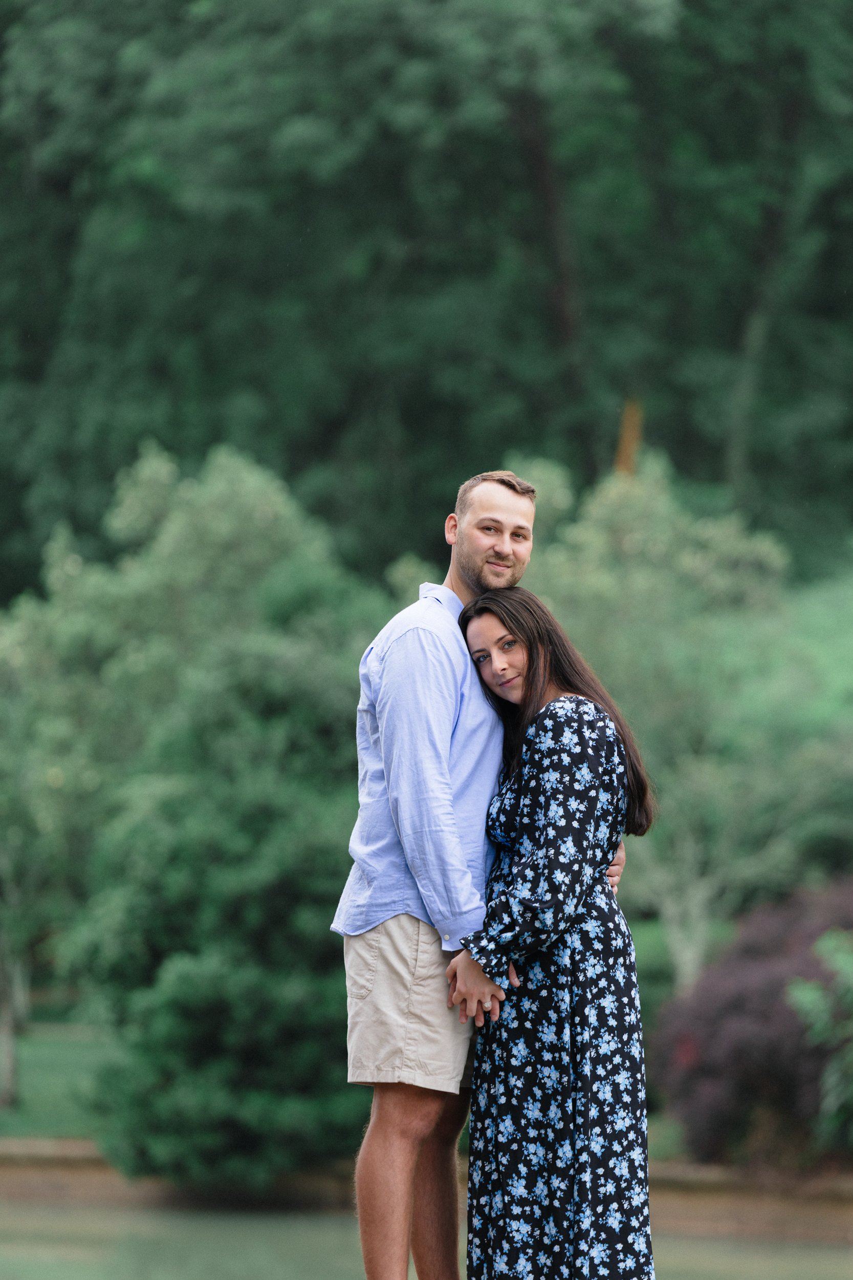 Newly engaged couple holding each other with natural smiles at the camera with Freedom Park outdoors in the background after he proposed, by ParksPictures