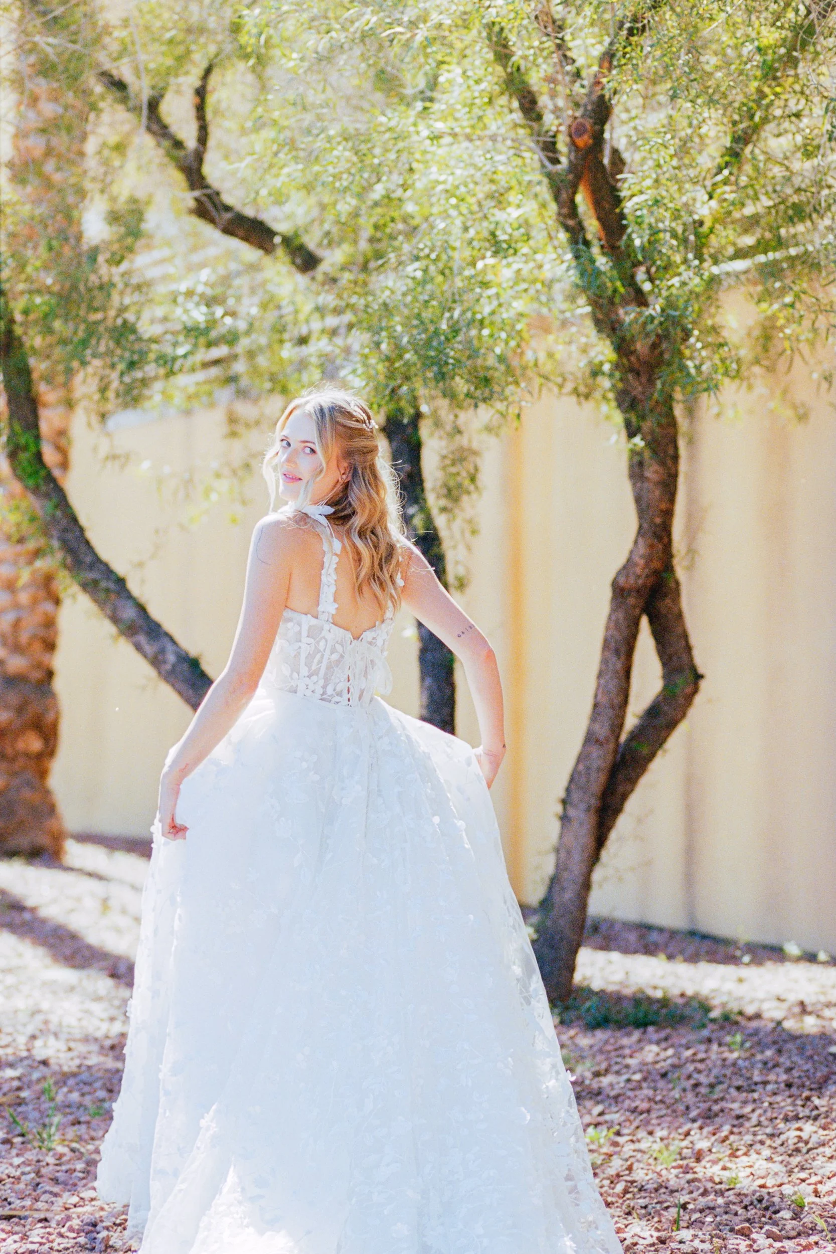 Bride looking over shoulder walking away in wedding dress with red and white bouquet Bridal portrait session photographed on Kodak Portra 400 film by ParksPictures
