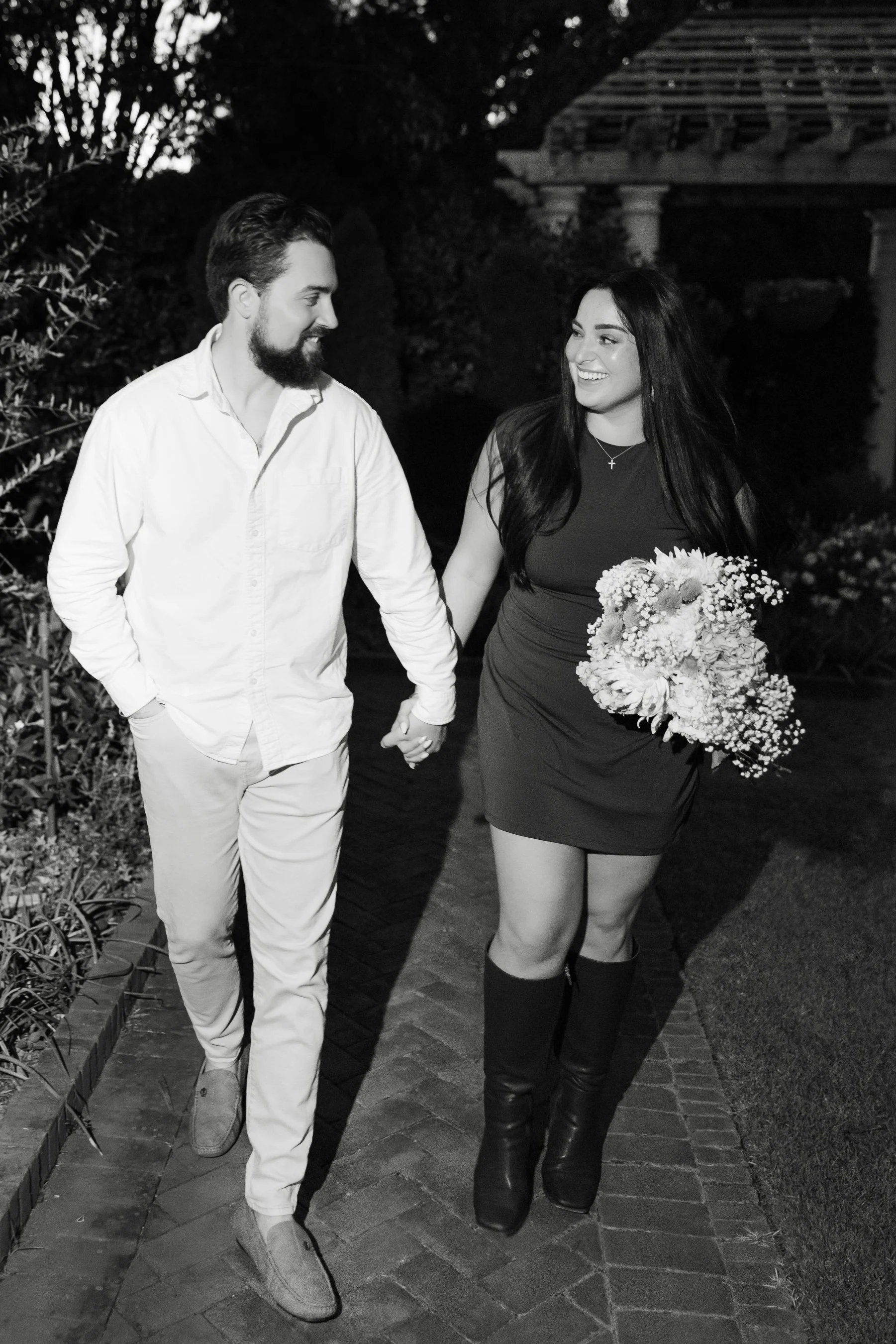 Engaged couple walking black and white garden arbor pergolas at Daniel Stowe Conservancy by Charlotte wedding photographer Michael Parks