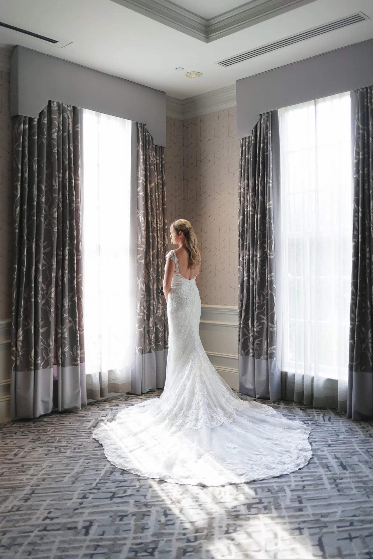 Bride looking out window getting ready at Carmel Country Club wedding on golf course by best Charlotte Wedding Photographer ParksPictures