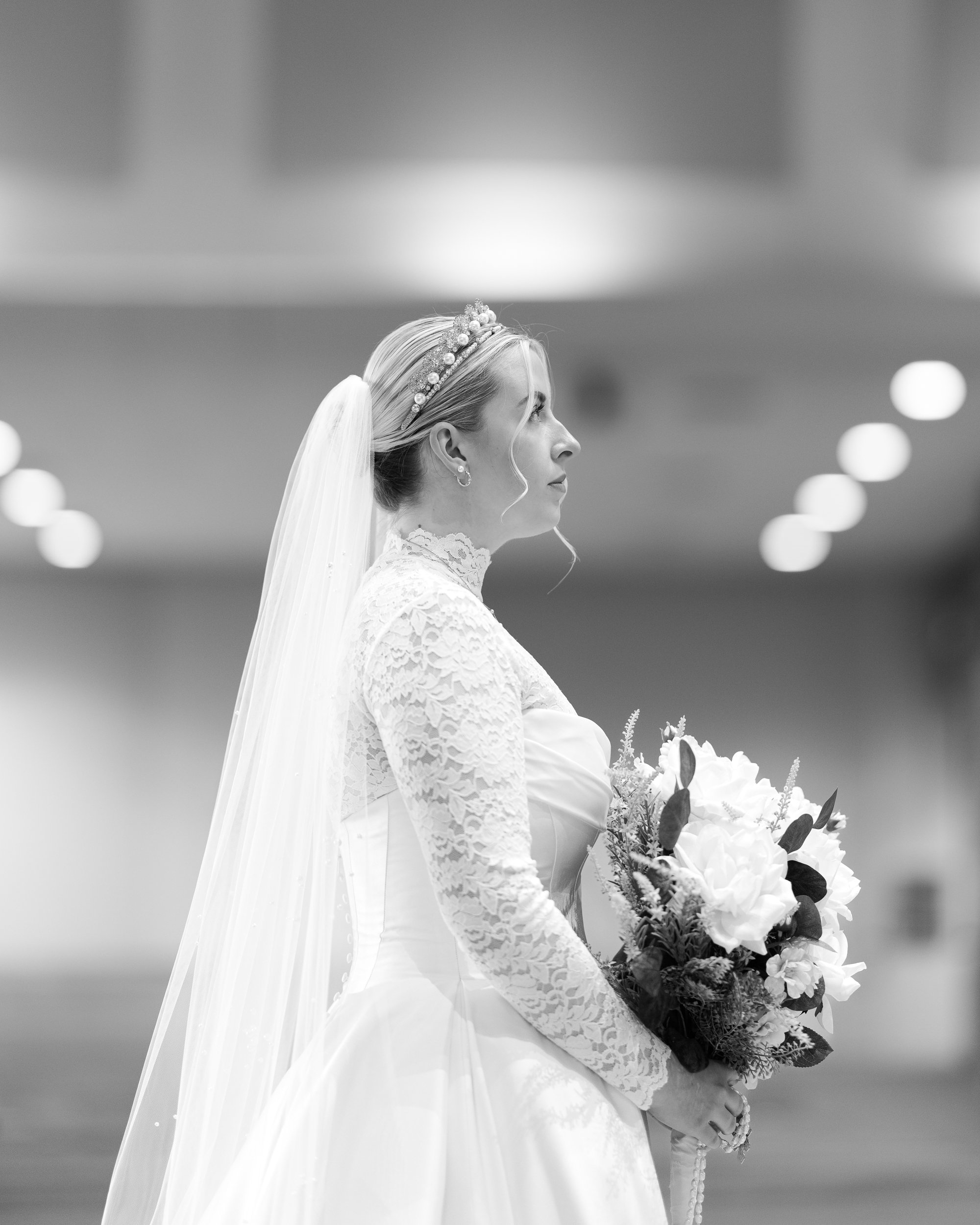 Bride looking at crucifix above altar holding her bouquet in her wedding dress with crown and veil for her bridal pictures
