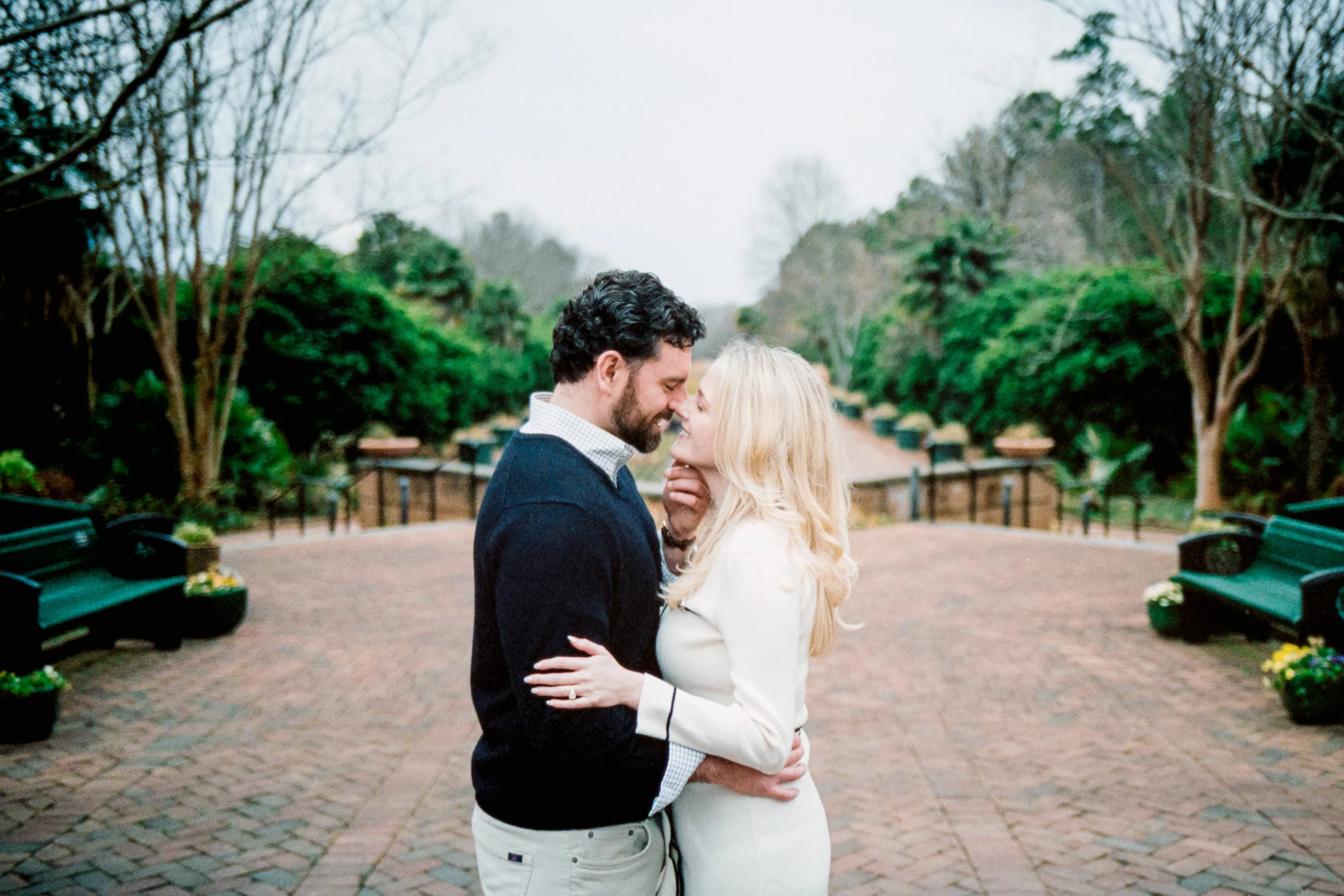 Newly engaged couple laughing and smiling at each other with Daniel Stowe Conservancy reflecting pond in the background after he proposed, on Kodak Portra 400 film by ParksPictures