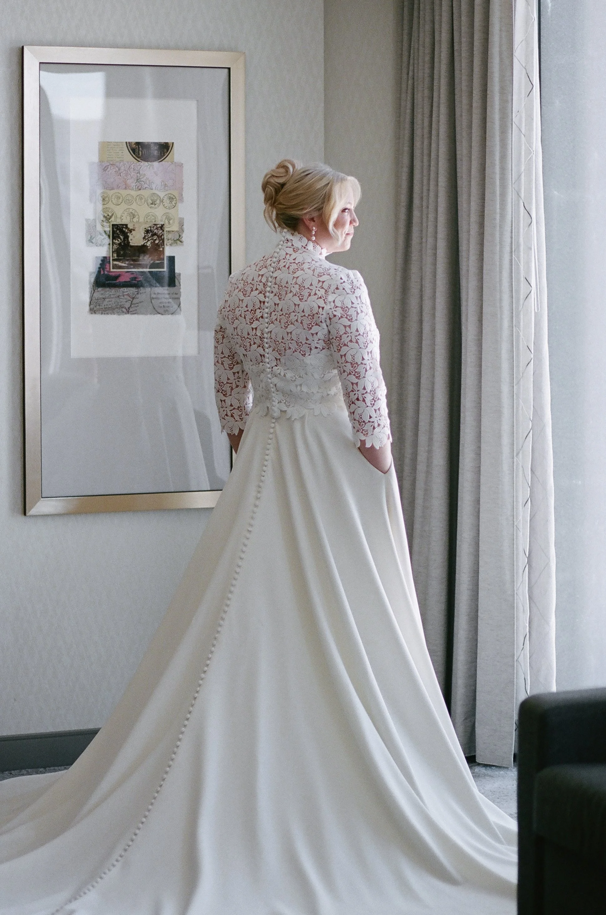 Bride getting ready in white dress with lace jacket before her wedding sacrament Mass at St. Peter Catholic Church in Uptown Charlotte NC on Portra 400 film by nearby Catholic wedding photographer ParksPictures
