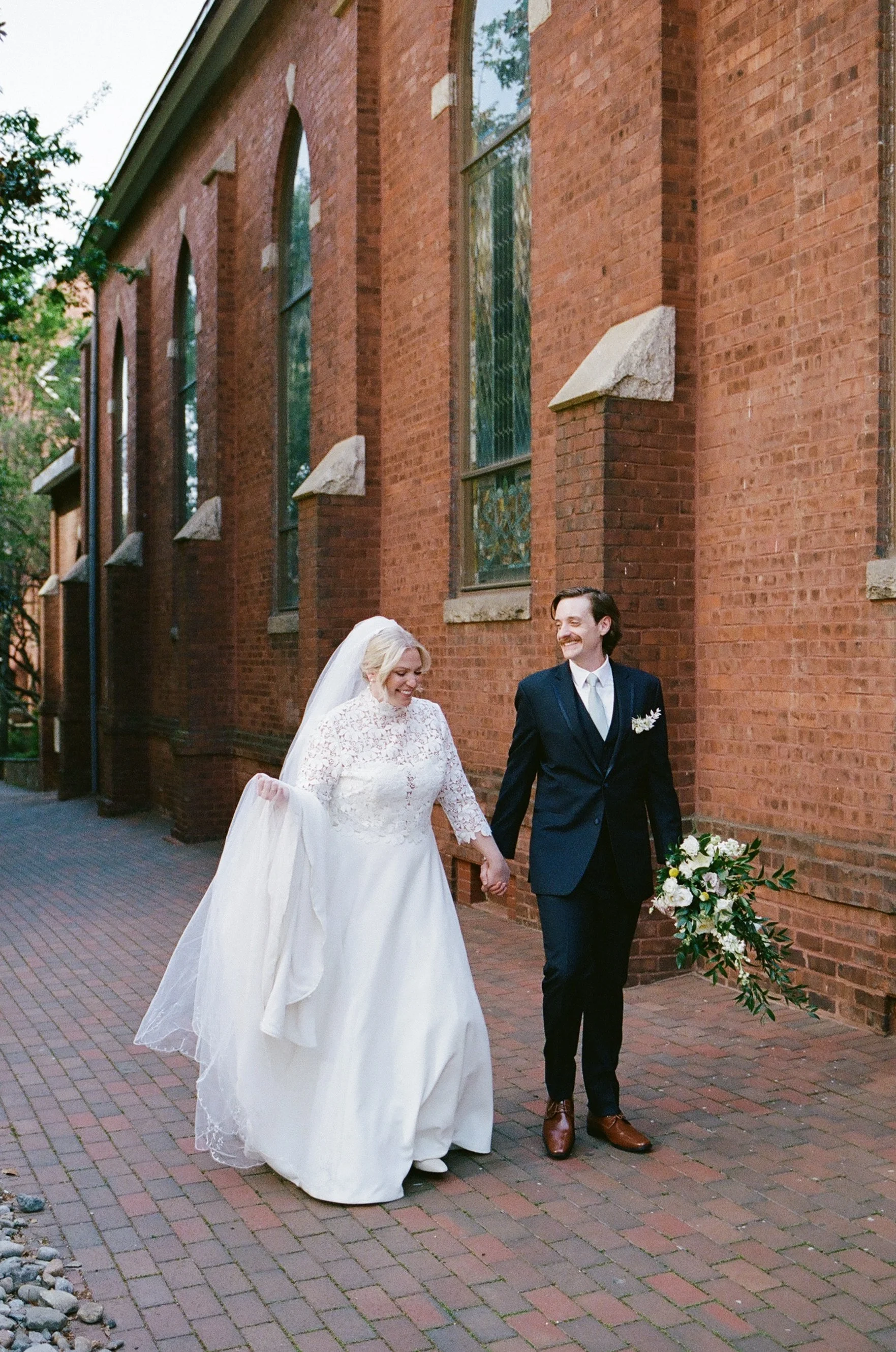 Bride and groom laughing outside St. Peter Catholic Church in Uptown Charlotte NC on Portra 400 film by nearby Catholic wedding photographer ParksPictures
