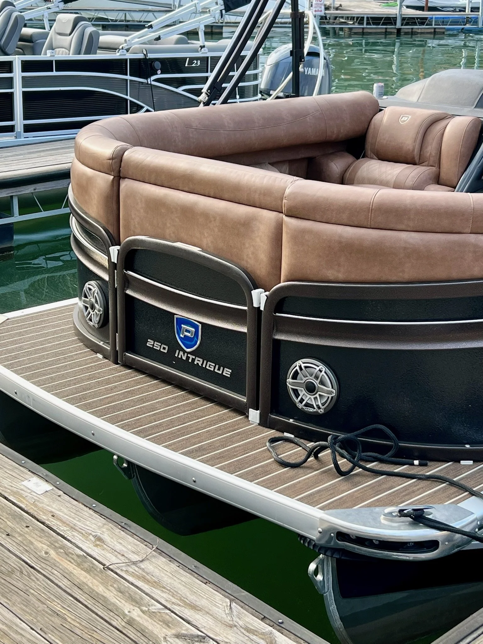 A pontoon boat tied to a dock, with brown leather seating, still in the water at a marina.
