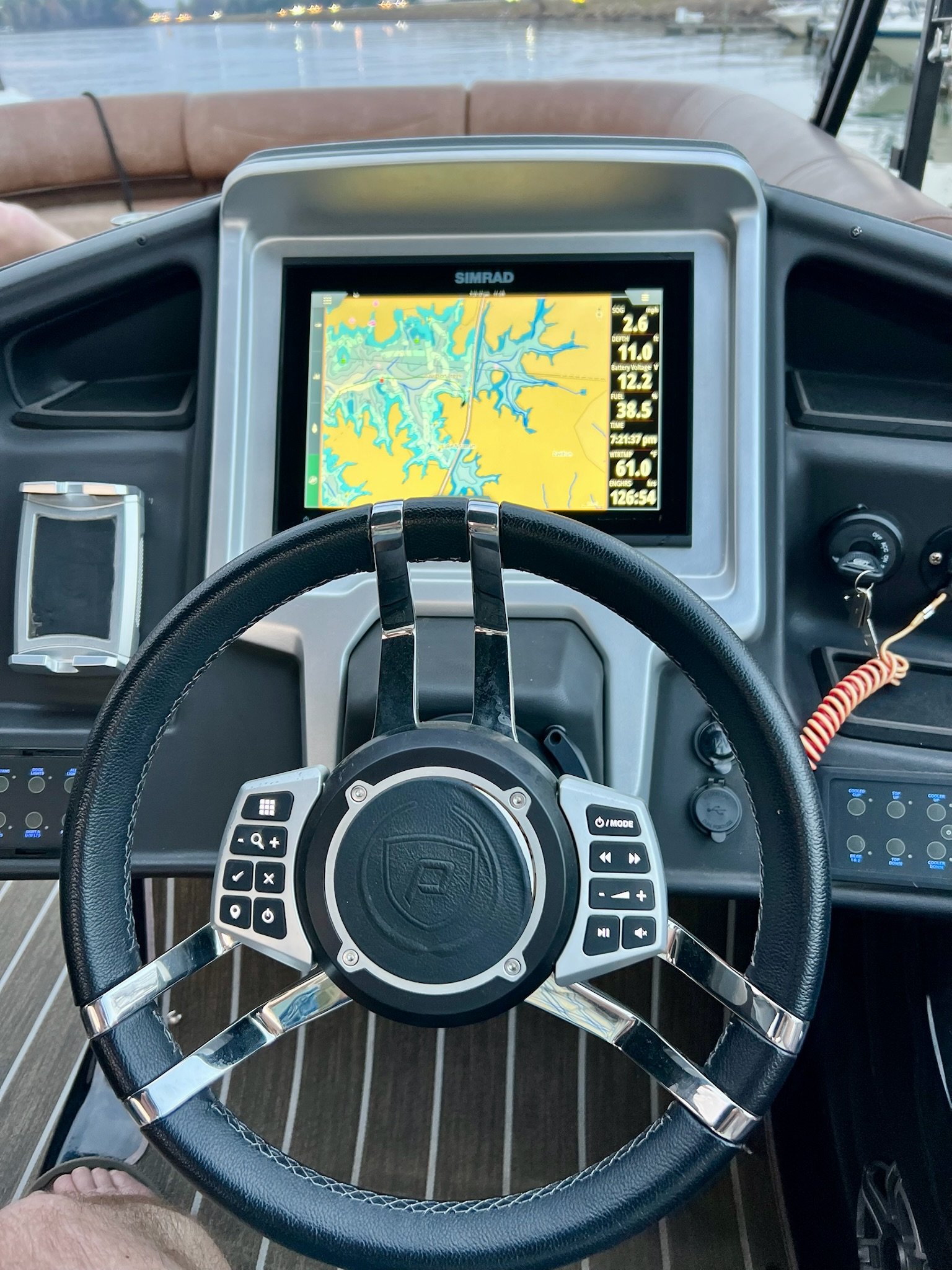 Boat dashboard with a steering wheel, a GPS screen showing a waterway map, and other navigation and engine control panels.
