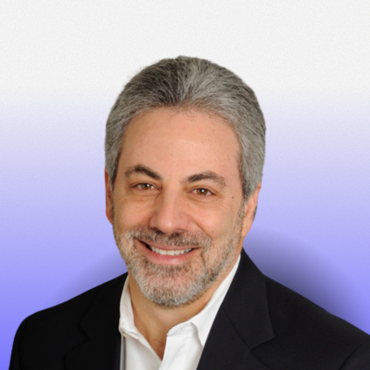 Headshot of a smiling middle-aged man with gray hair and a beard, wearing a dark suit jacket and white shirt, against a gradient background from light gray to blue.