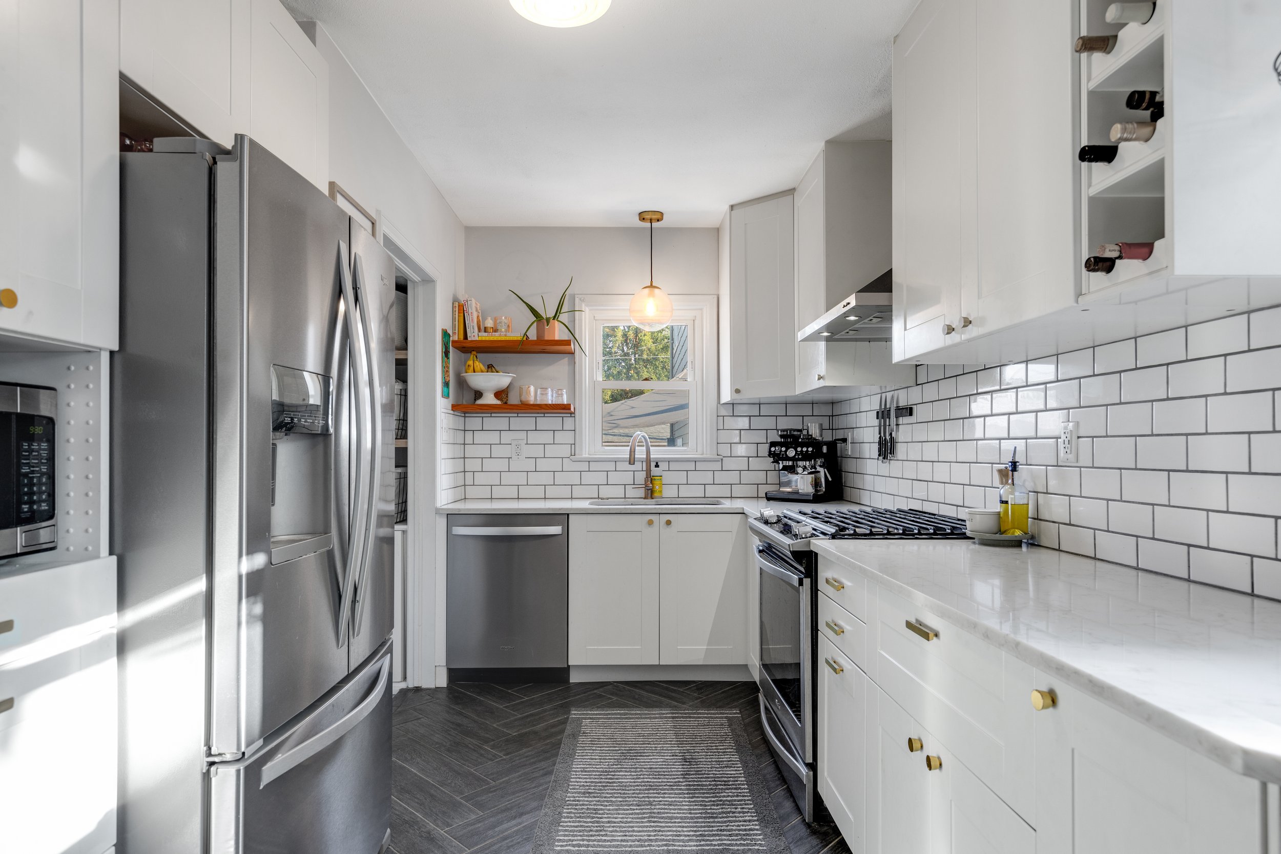 Modern kitchen with white cabinets, stainless steel appliances, white subway tile backsplash, and dark wood flooring.