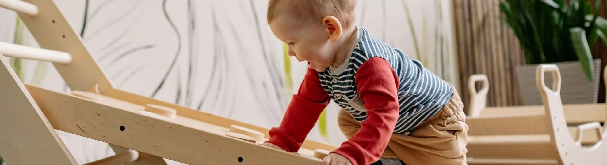 toddler climbing a wooden toy in a classroom