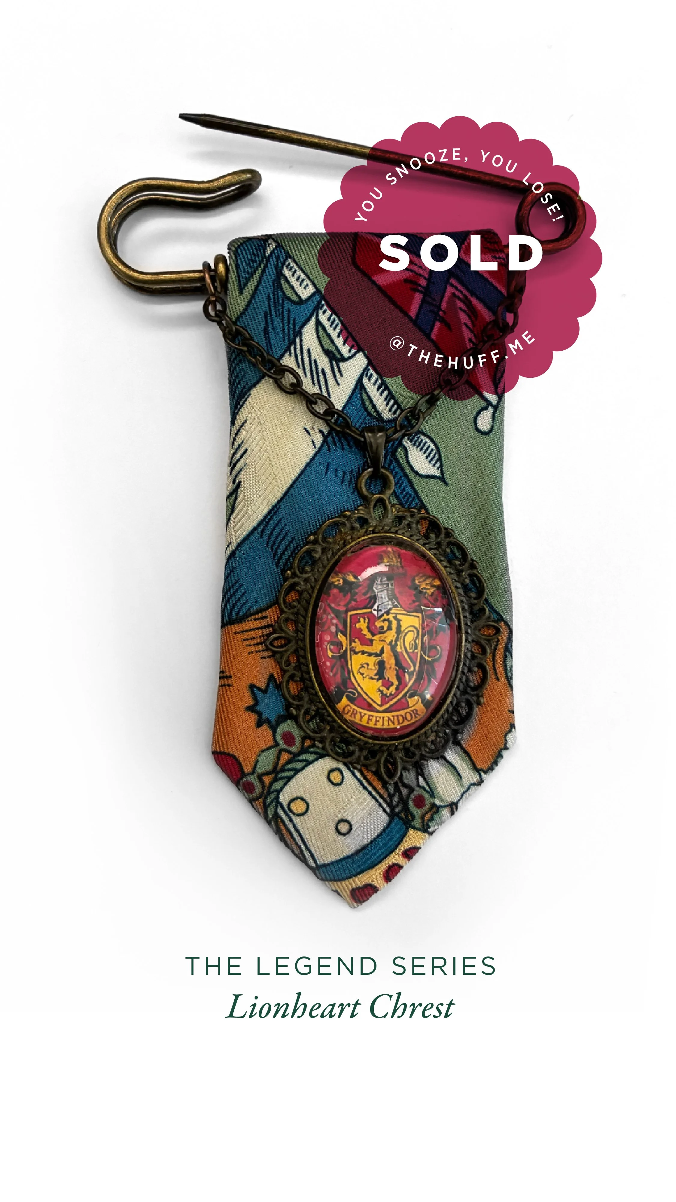 A Harry Potter Gryffindor crest necklace with a chain, pendant, and fabric background, tagged as sold and part of The Legend Series Lionheart Chest.