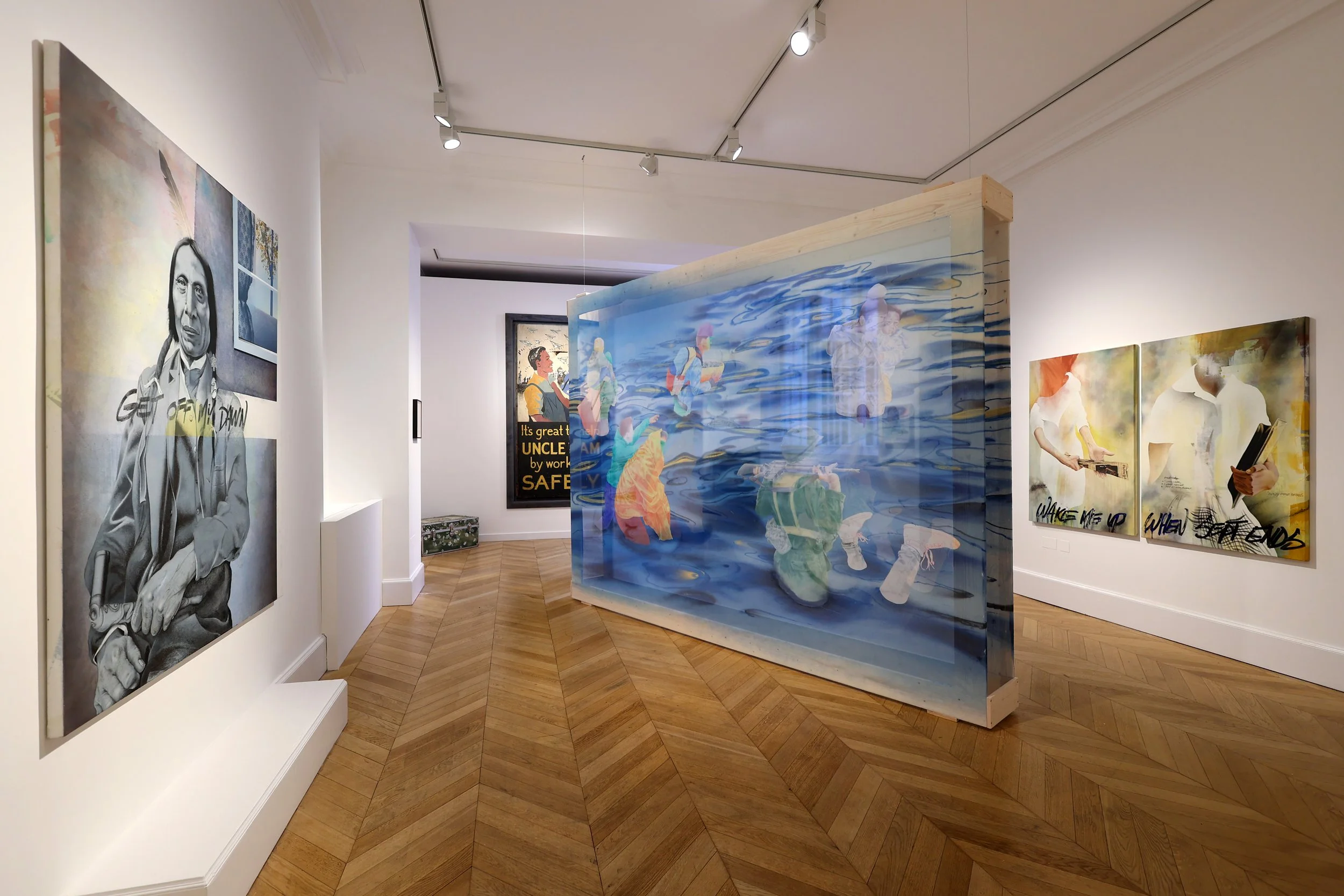 Contemporary art gallery displaying various paintings, including a black-and-white portrait of a person in traditional attire, and colorful, abstract artworks; a glass sculpture with painted figures inside is also visible.