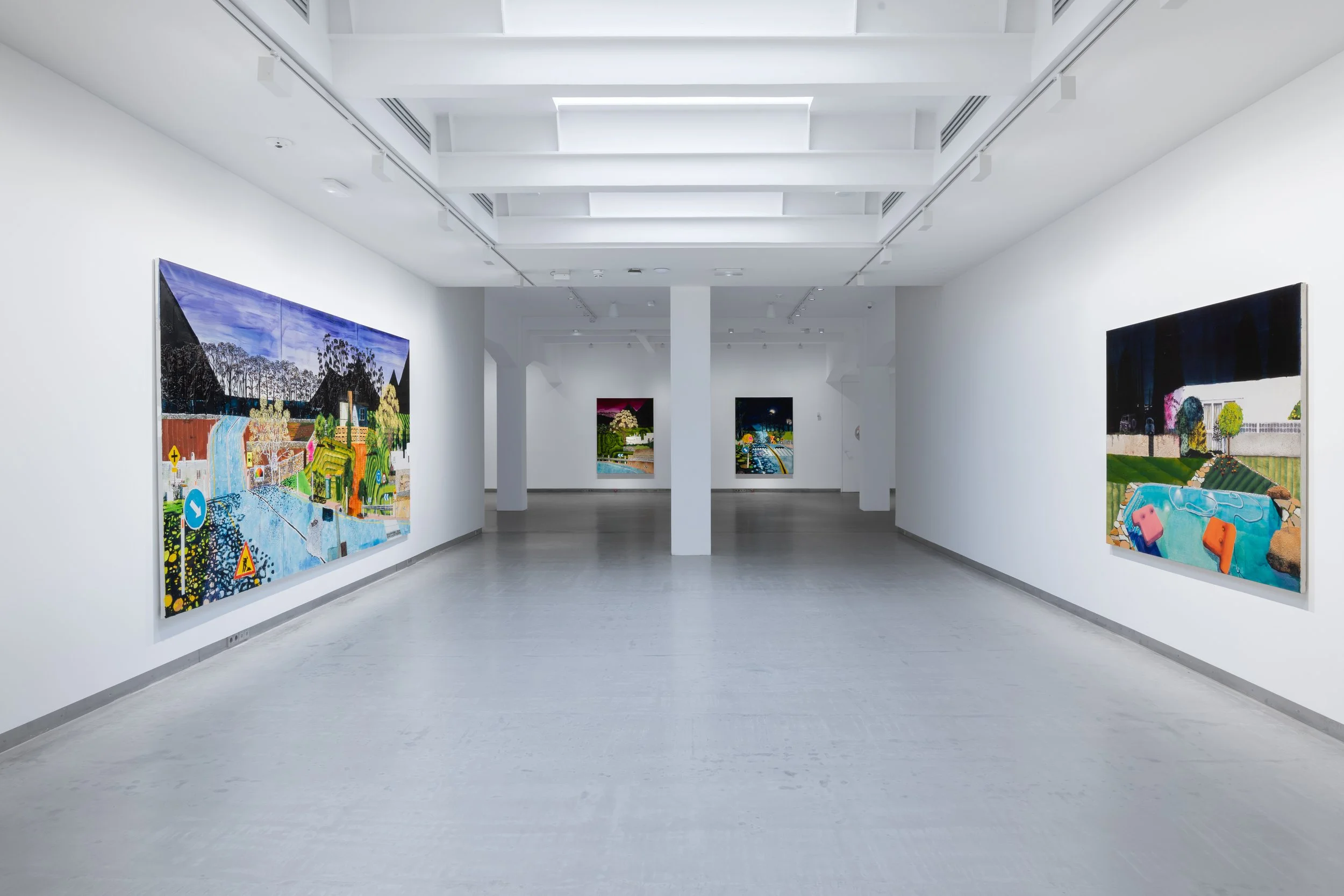 Colección Solo, Bowman Hal. View of an art gallery with white walls and a gray floor, displaying colorful paintings.