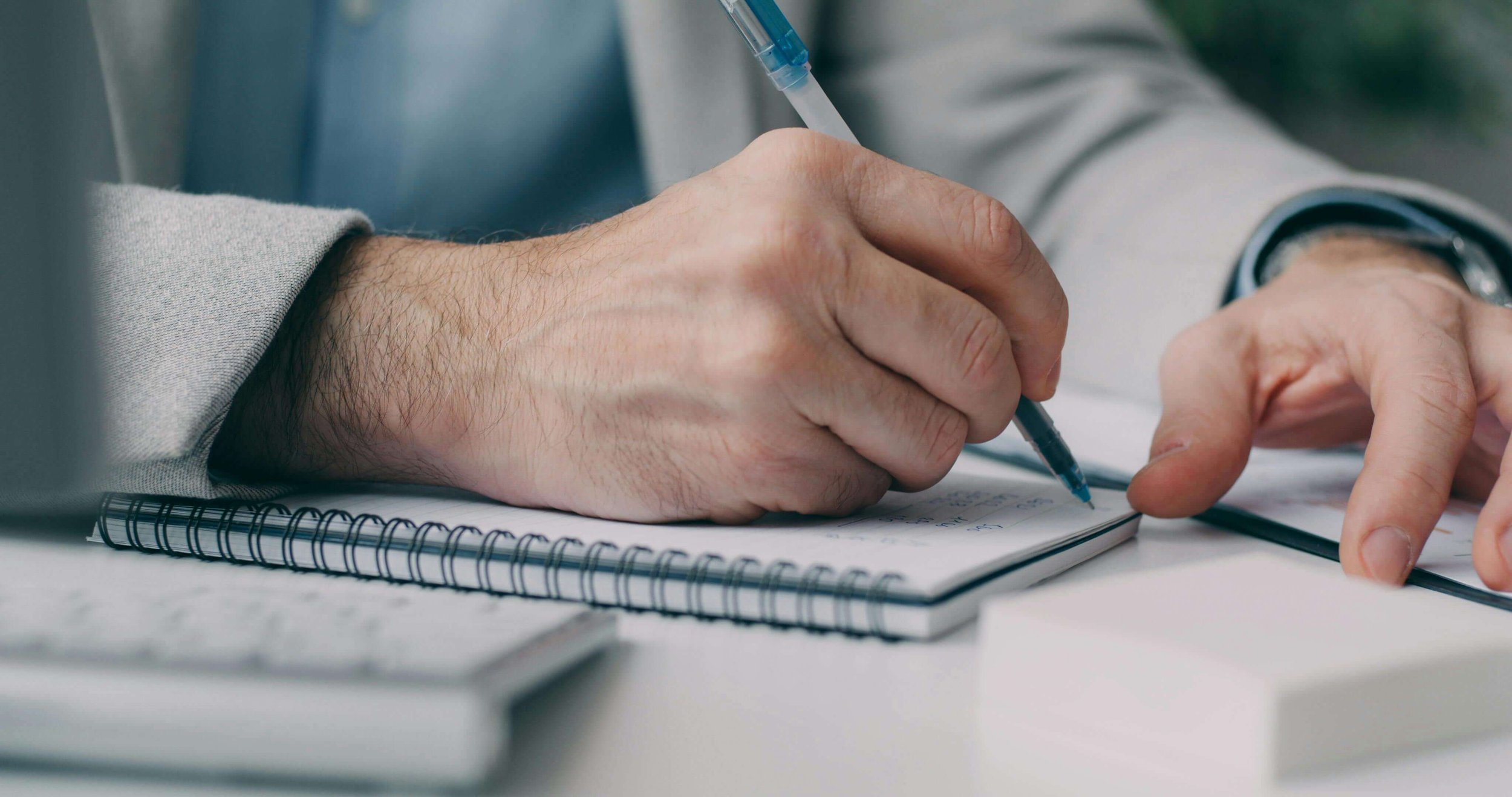 Man's hands writing notes in notebook.