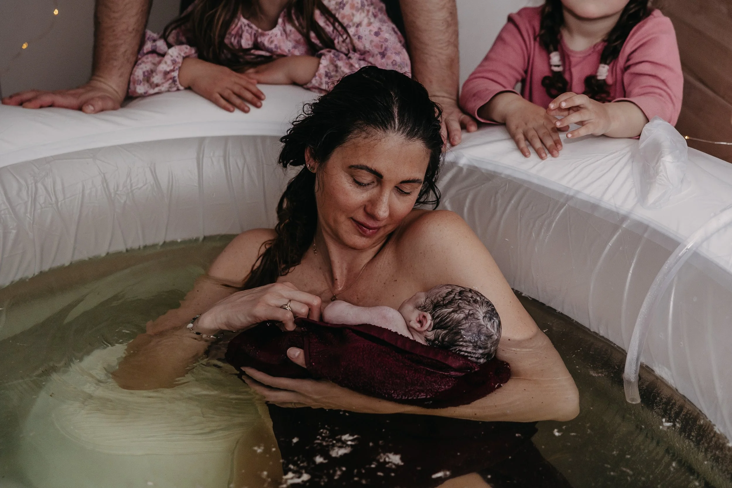 Geburtsfotografin in Hannover fotografiert eine Frau, die ihr Baby im Geburtspool geboren hat.