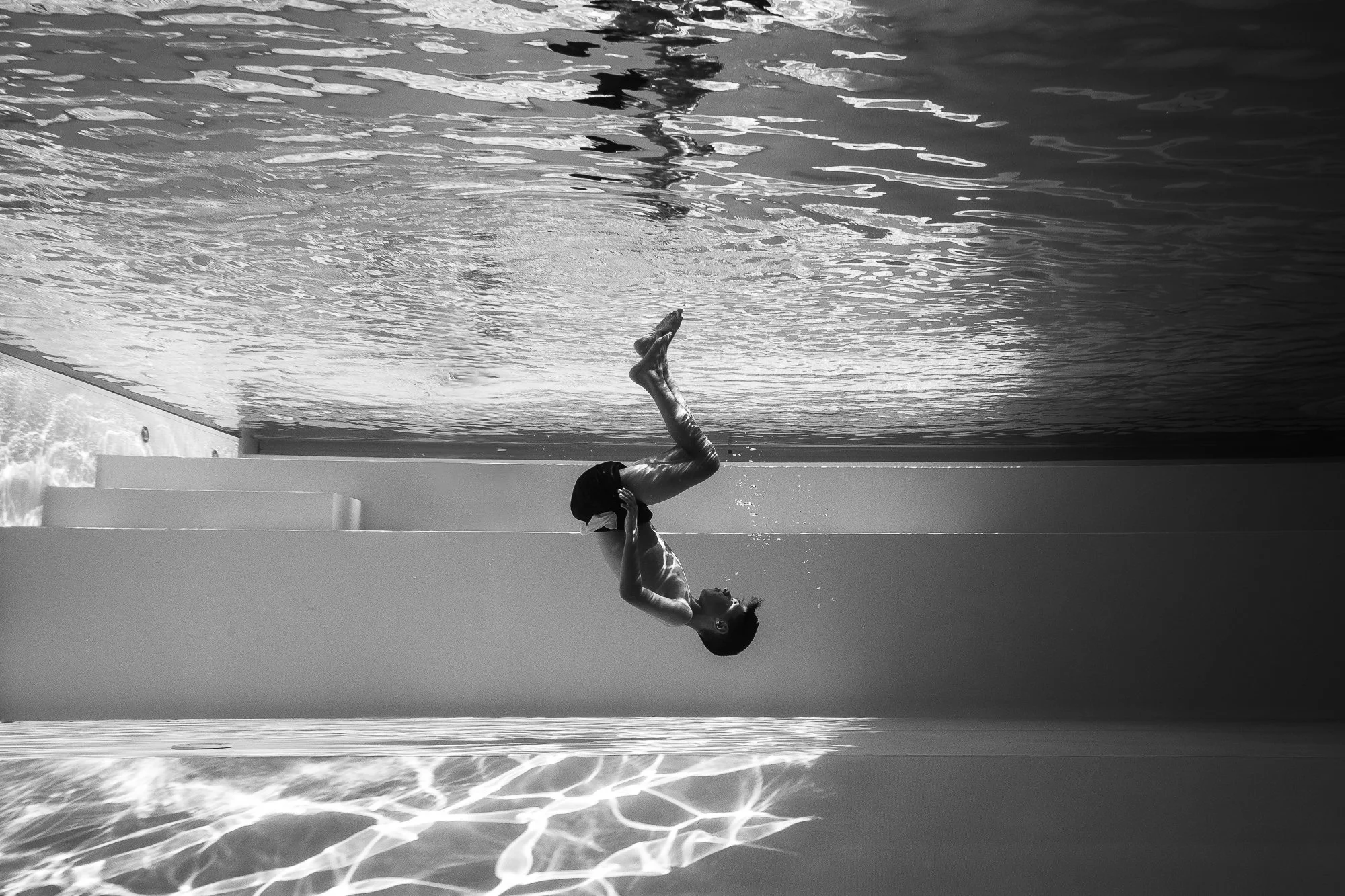 Junge taucht unter Wasser im Schwimmbad