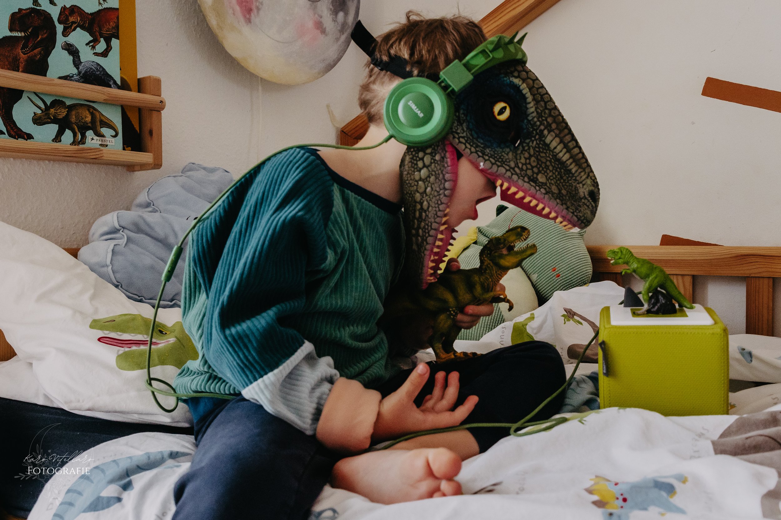 Kind im Dinokostüm spielt mit Dinos