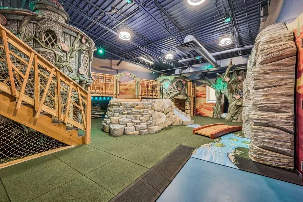 An elaborate, whimsical indoor playroom by Charmed Playhouses featuring an enchanted forest theme.