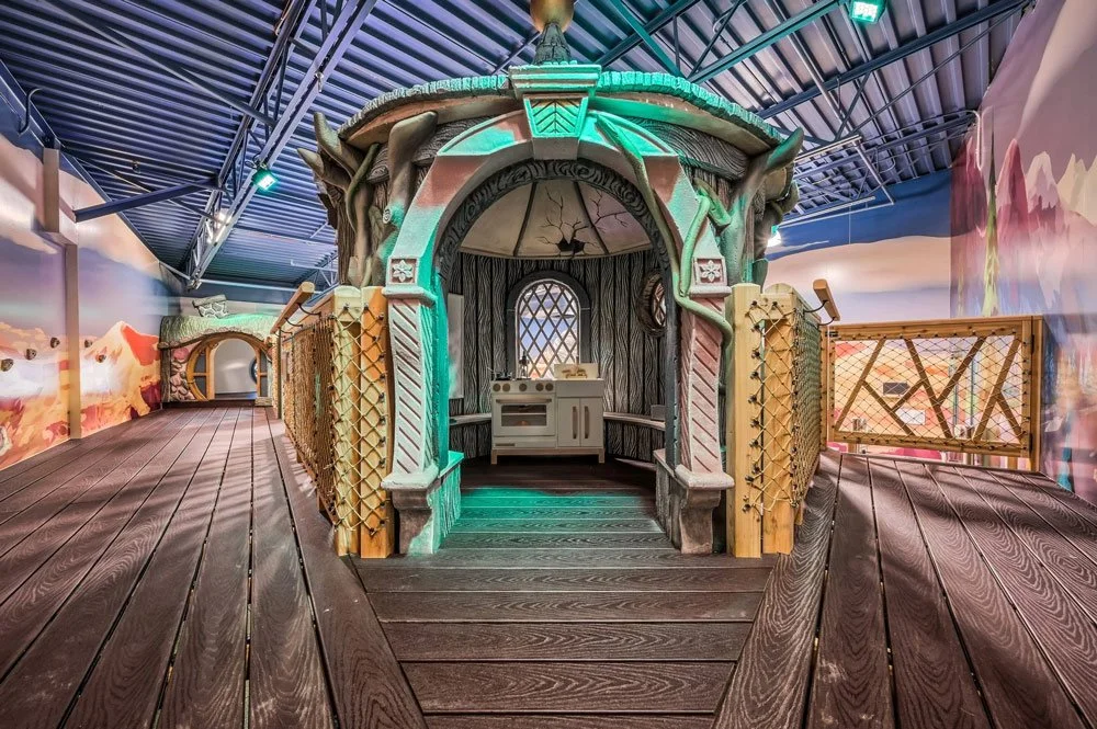 An elaborate, whimsical indoor playroom by Charmed Playhouses featuring an enchanted forest theme.