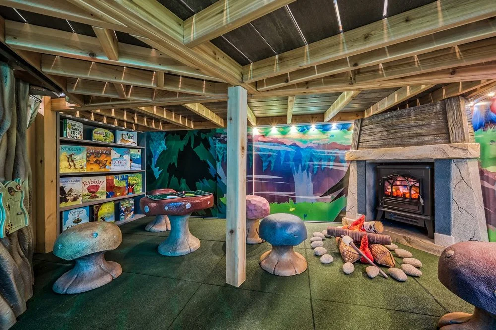 An elaborate, whimsical indoor playroom by Charmed Playhouses featuring an enchanted forest theme.