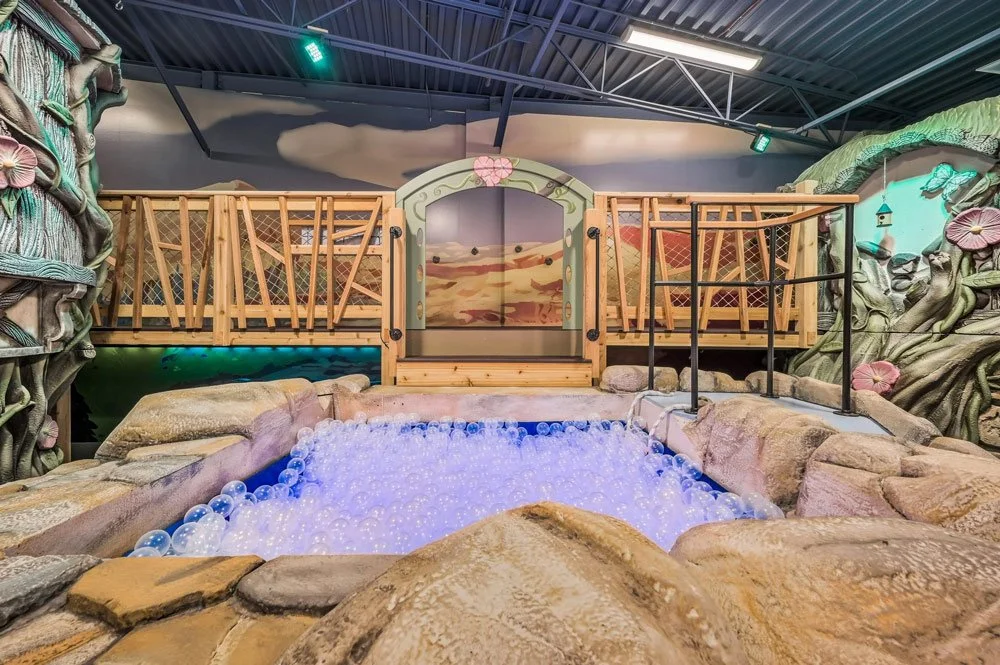 An elaborate, whimsical indoor playroom by Charmed Playhouses featuring an enchanted forest theme.