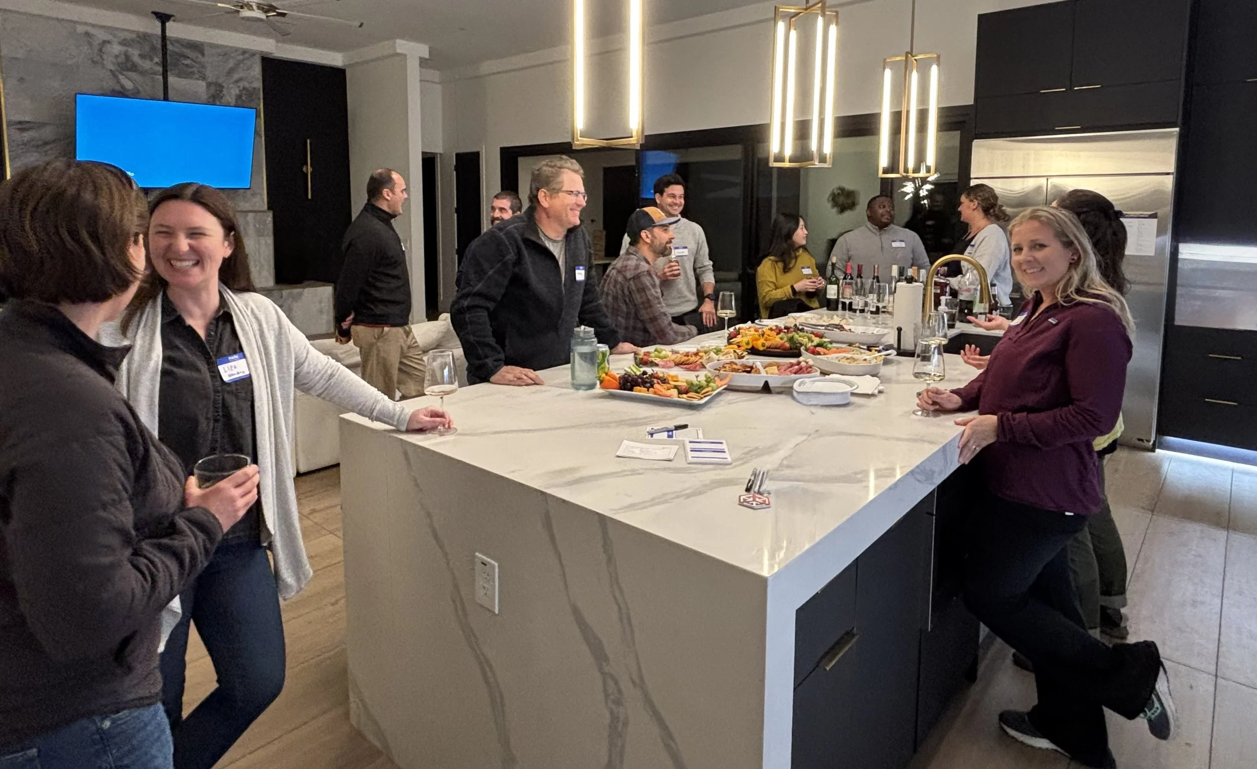 People gathering in a modern kitchen celebrating with drinks, food, and conversation.