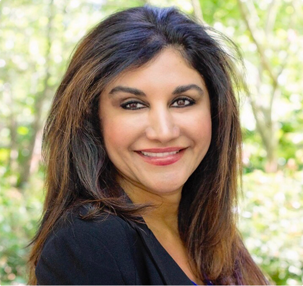 Lotus Blossom Hospice co-founder and administrator, Susan Taba, smiling outdoors, with green trees in the background.