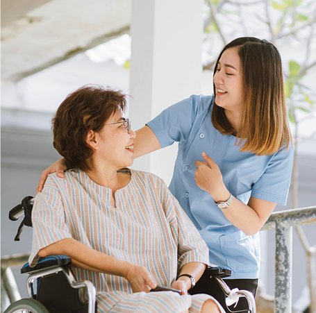 A young nurse smiling and talking with an older woman in a wheelchair while providing palliative care in metro Atlanta.