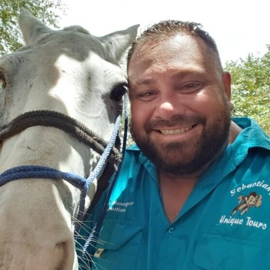 Tour Guide and Company Founder, Sebastian, smiling next to a horse