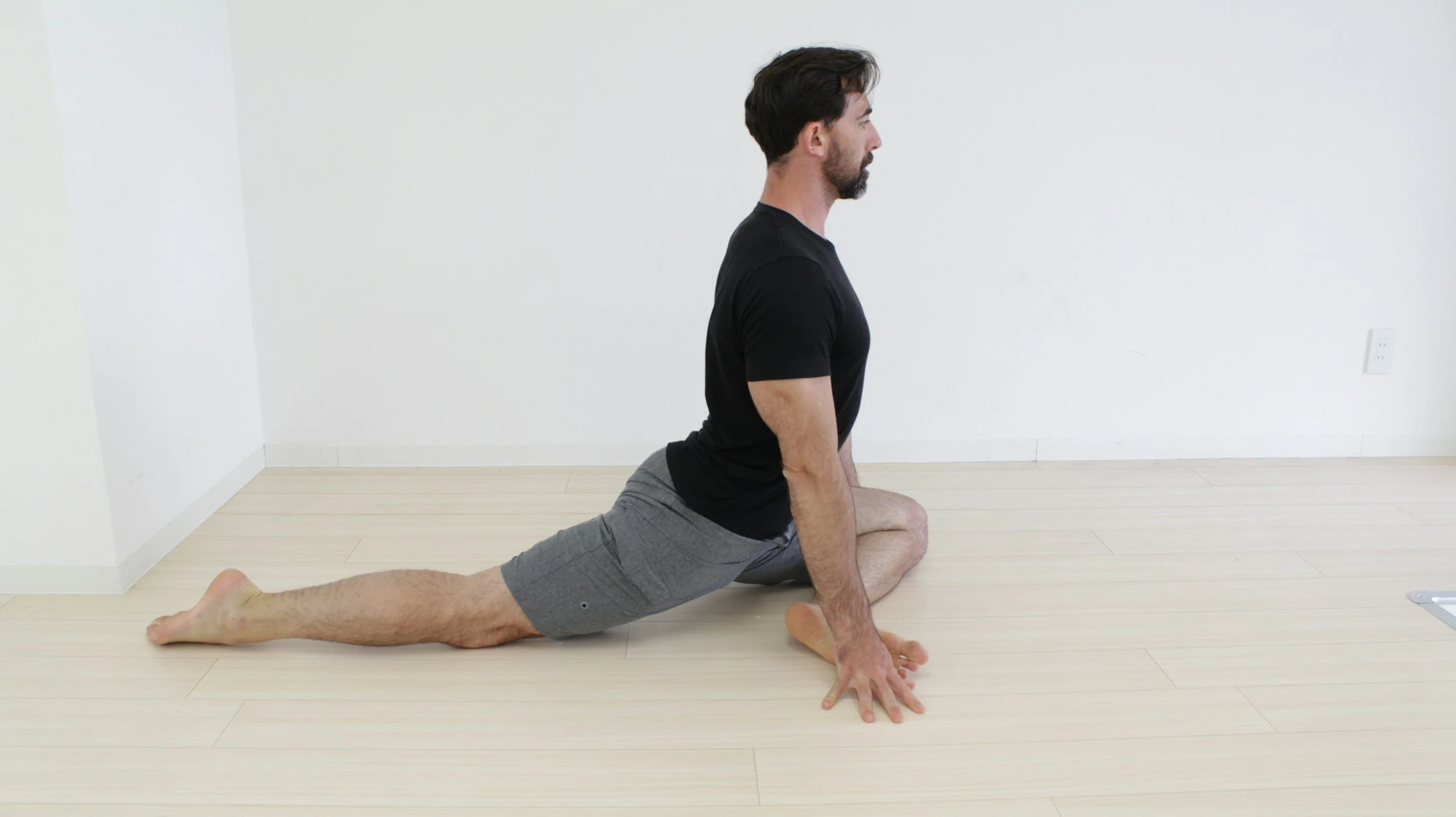 A man in a deep hip stretch while on the floor