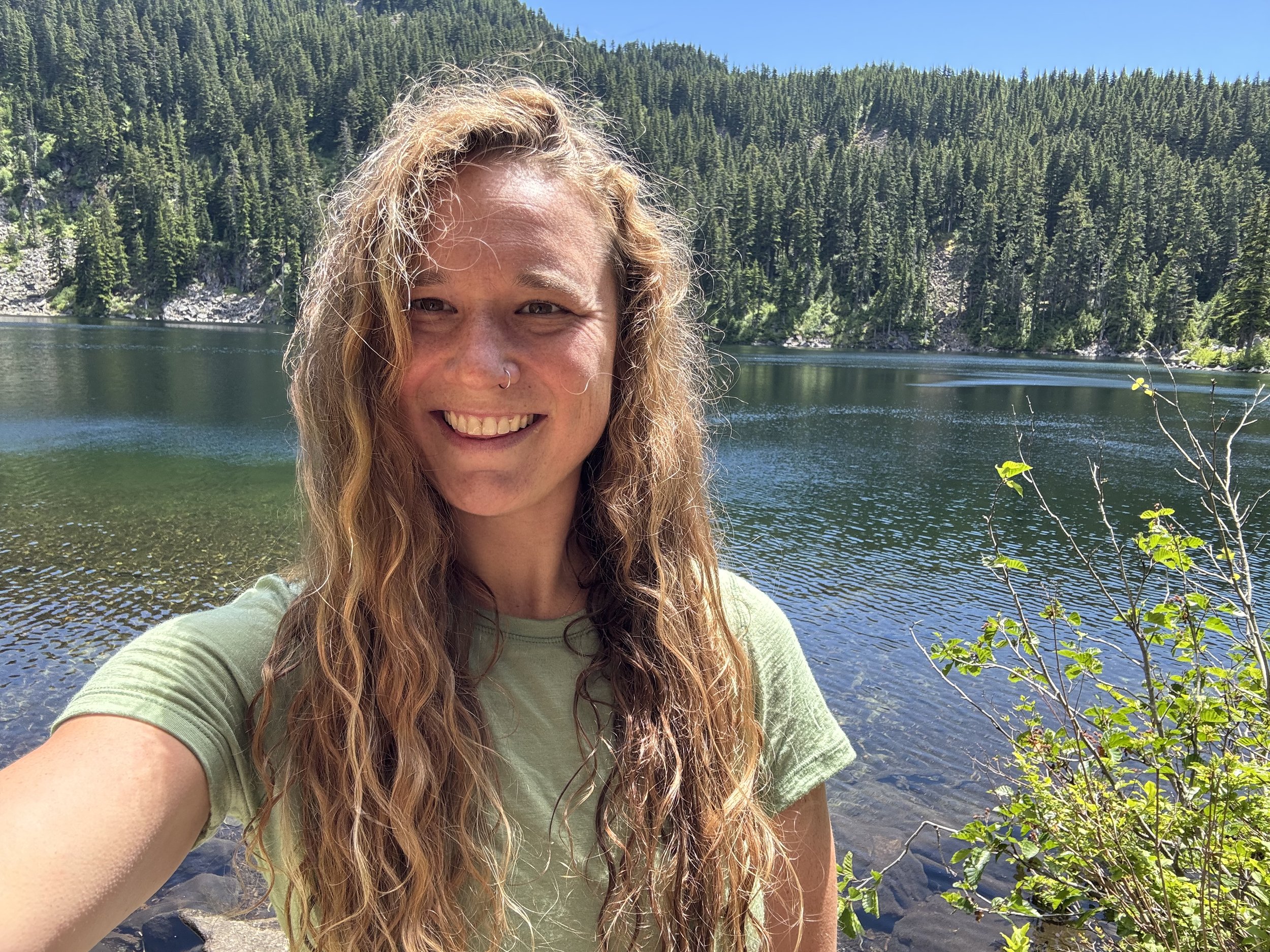 Tori standing in front of a lake on a sunny day, smiling.