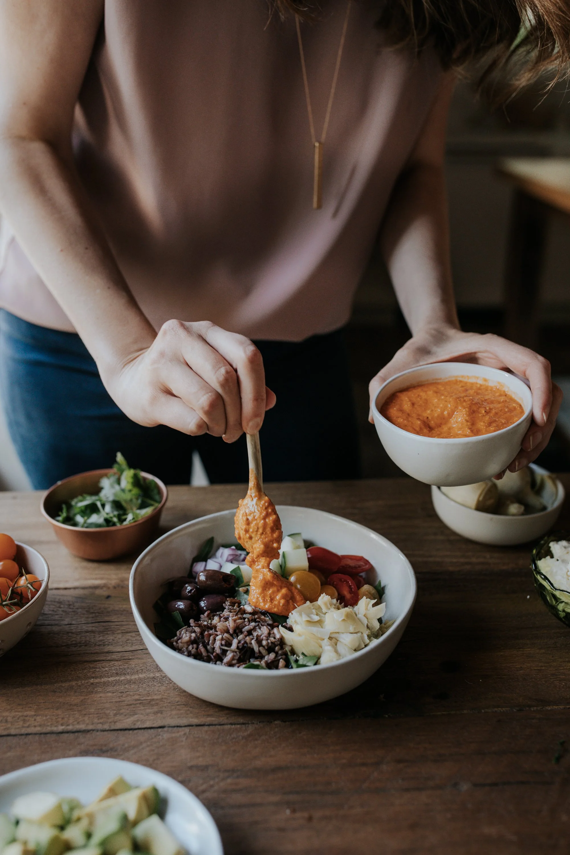 Hilary spooning sauce onto a bowl of food.