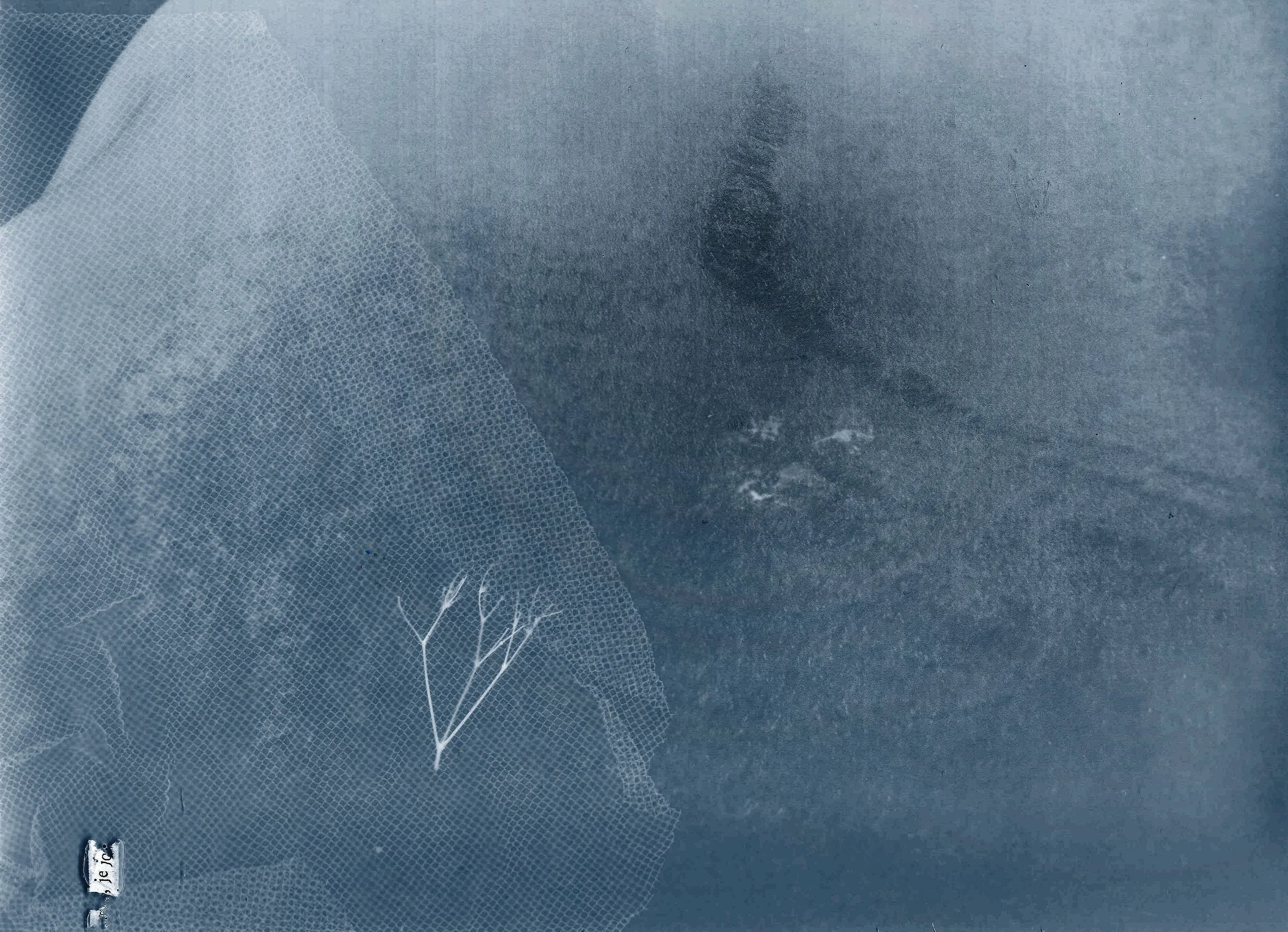 Photo en noir et blanc d'une personne, avec des traits de visage peu distincts, portant un masque en filet ou tissu léger.