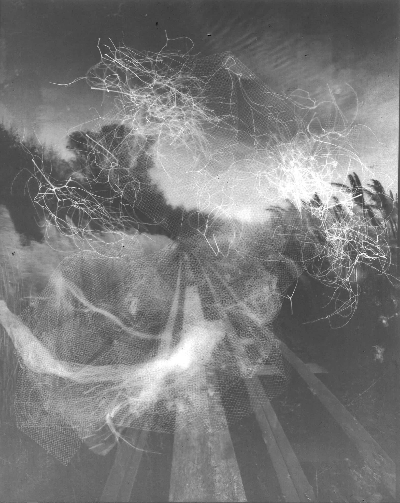 Une sculpture en fil métallique représentant une figure humaine, placée dans un environnement naturel en plein air, avec un ciel nuageux en arrière-plan.