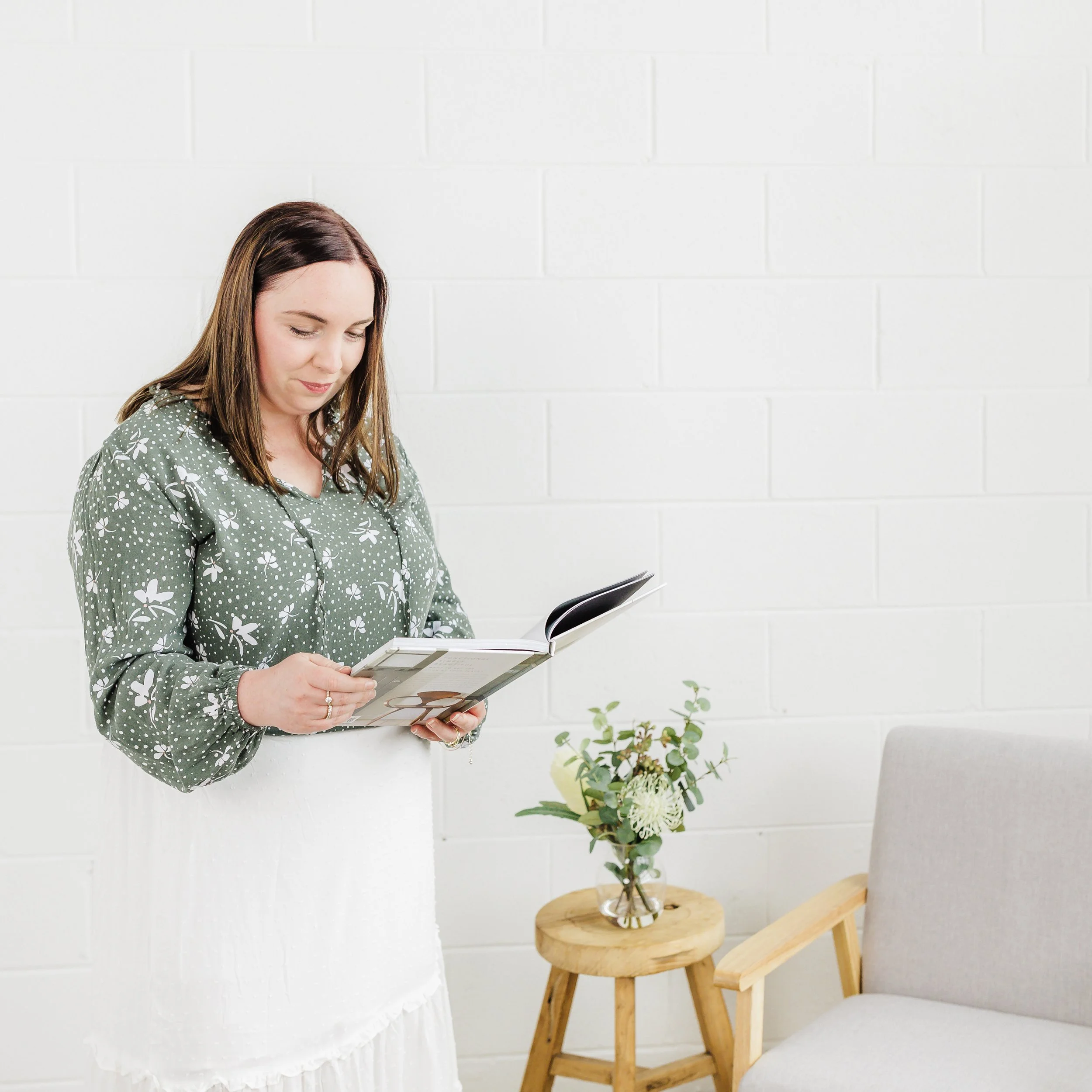 Woman looking at a book in her lounge room 