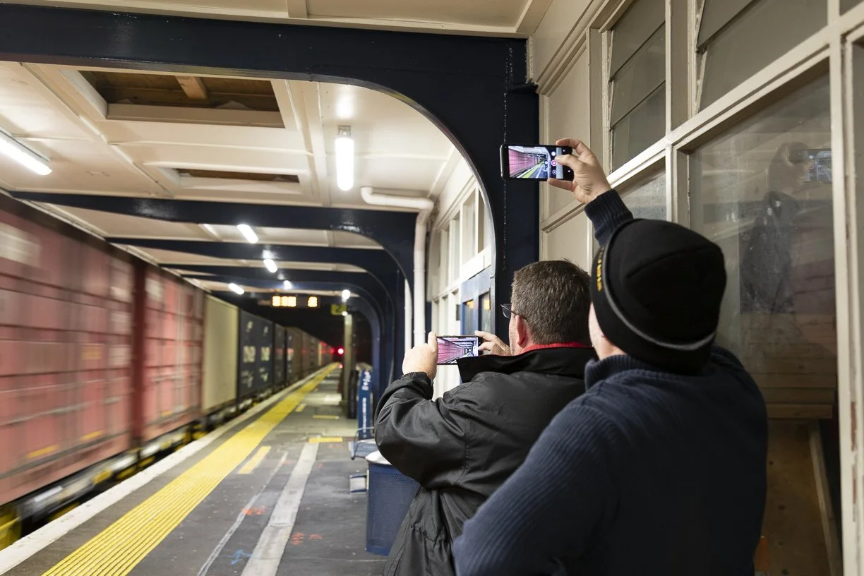 Two people videoing a Wellington bound freight train at night passing through the now demolished railway station.