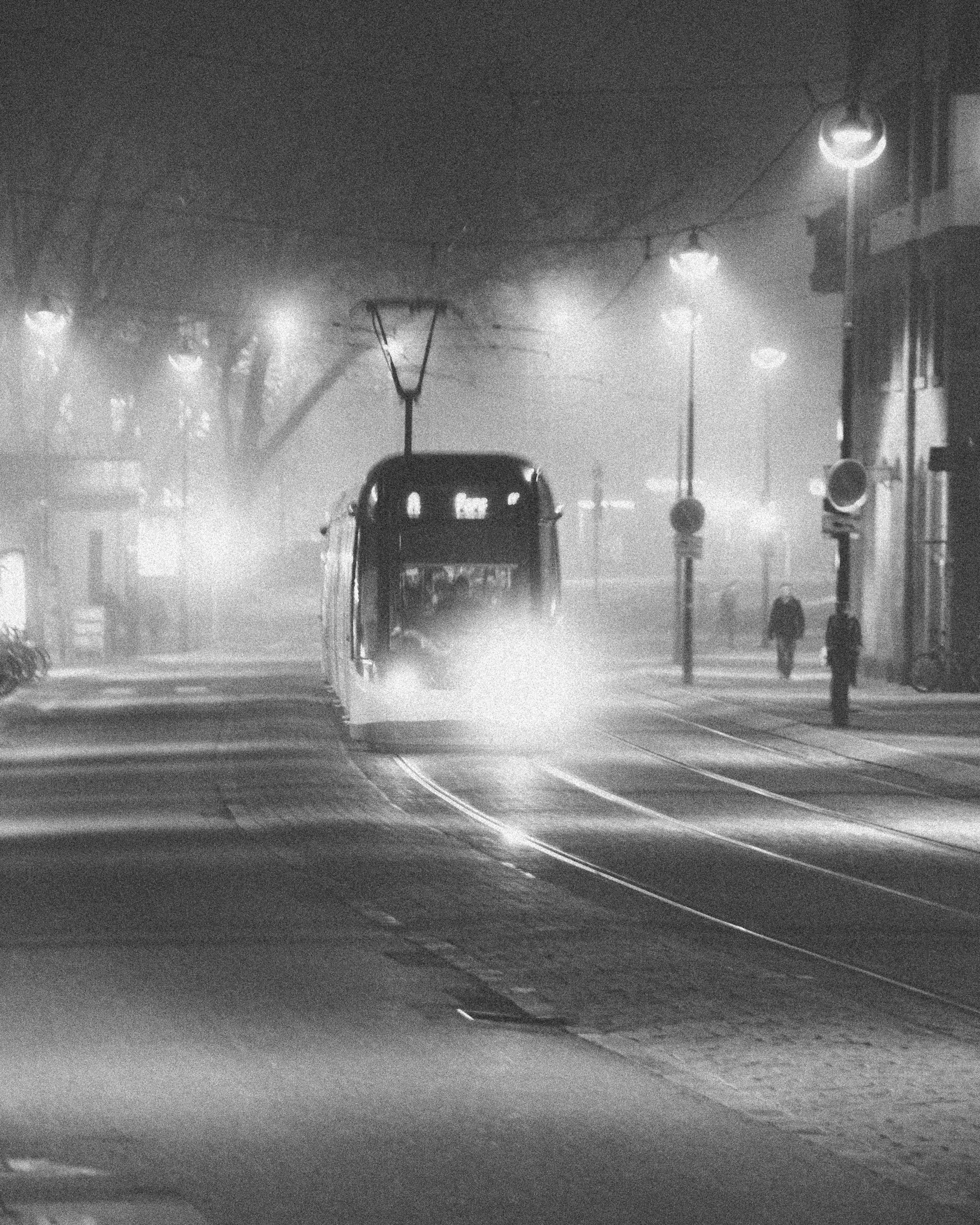 A Tram in the French city of Strasbourg lights up the rails on a dark foggy night as pools of light shine from the street lights black and white railway photography fine art photo taken by Scott Gould A Railway Life fine art photography train photo